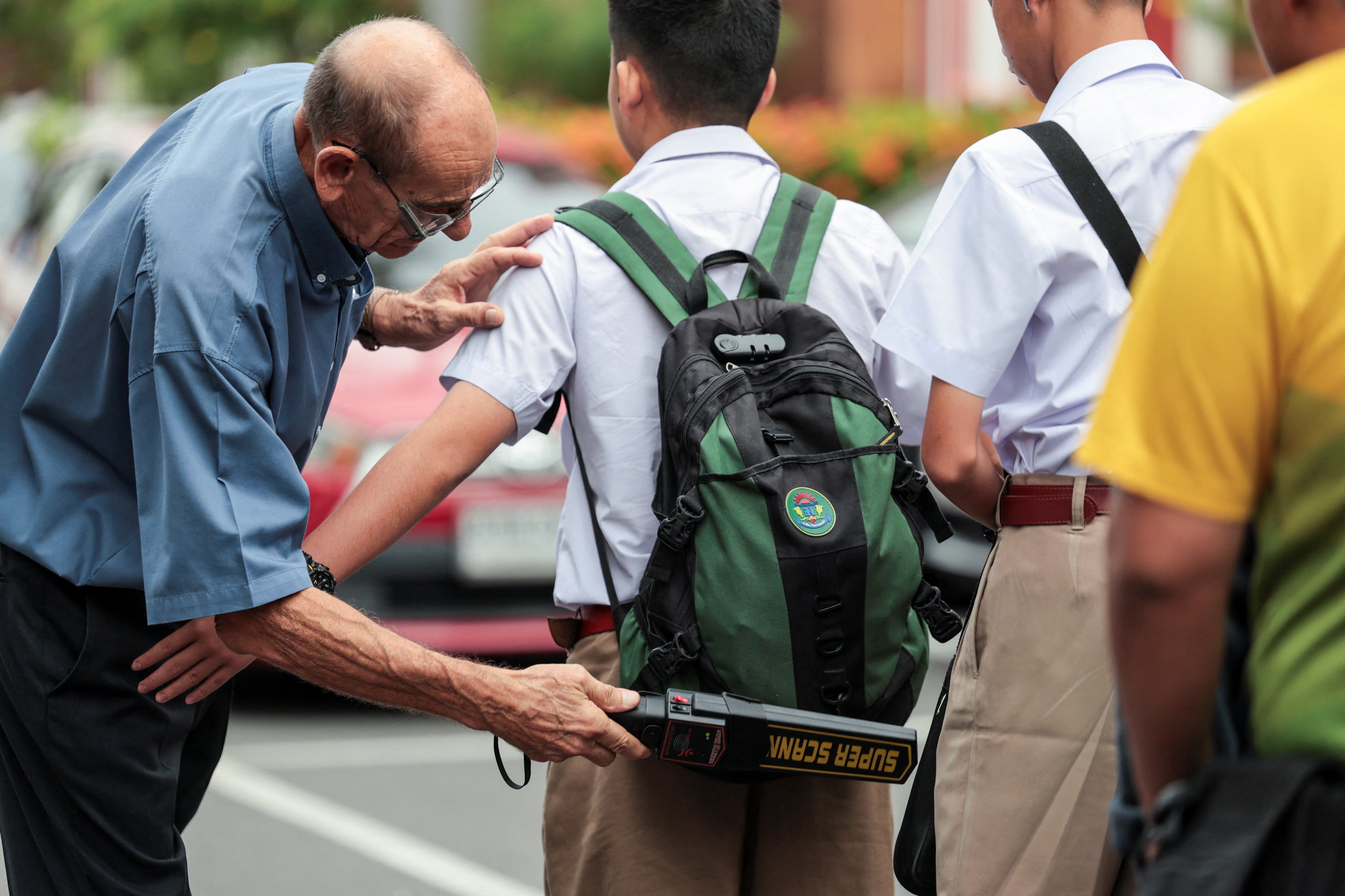 A teacher uses a metal detector to screen for weapons as students enter a school in Bangkok on Monday, following a deadly shooting at Debsirin school in Nonthaburi province. Photo: Reuters