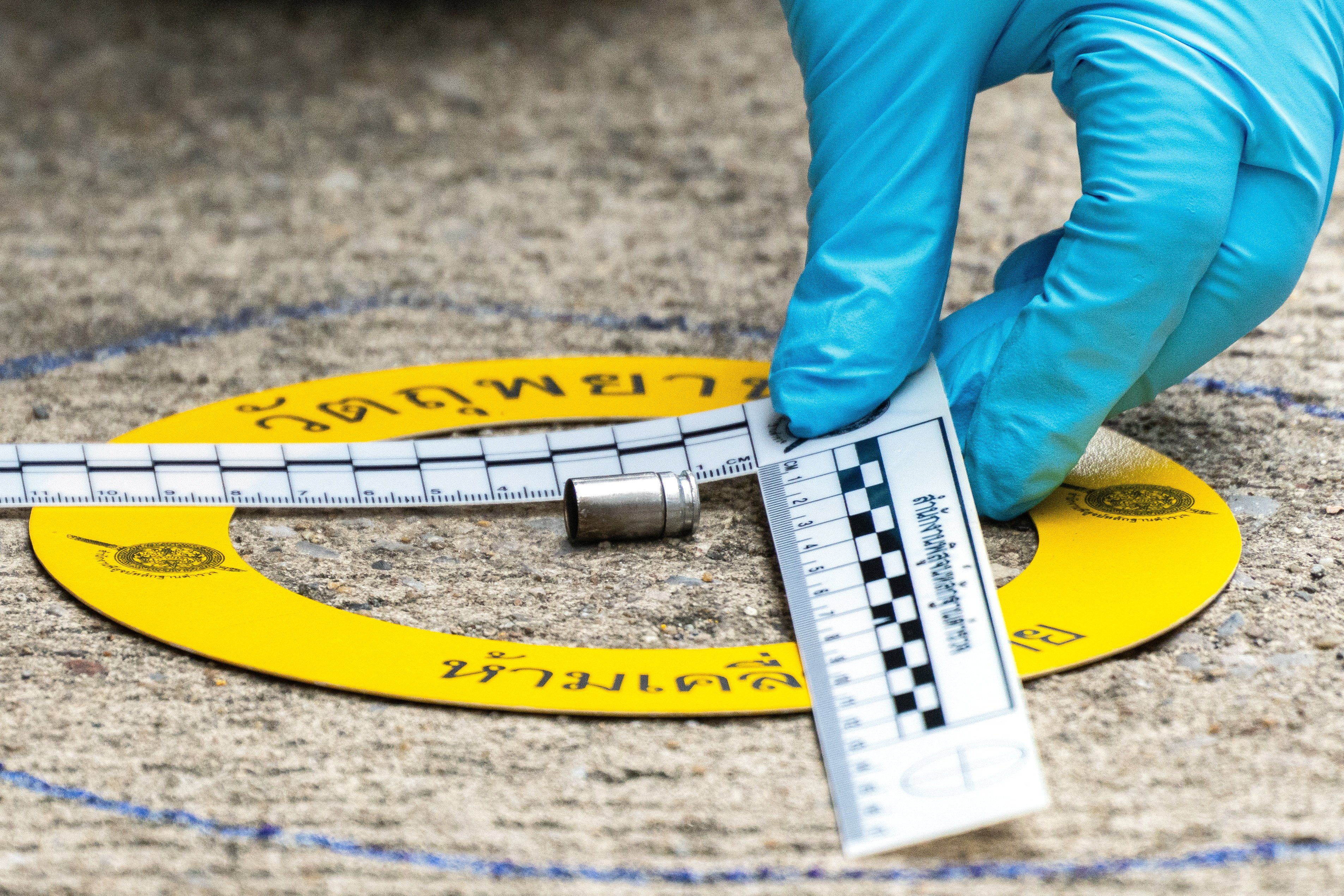 A forensic police officer marks a bullet casing as evidence at the site of a shooting at the Nonthaburi Provincial Administrative Organisation office on Monday. Photo: Reuters