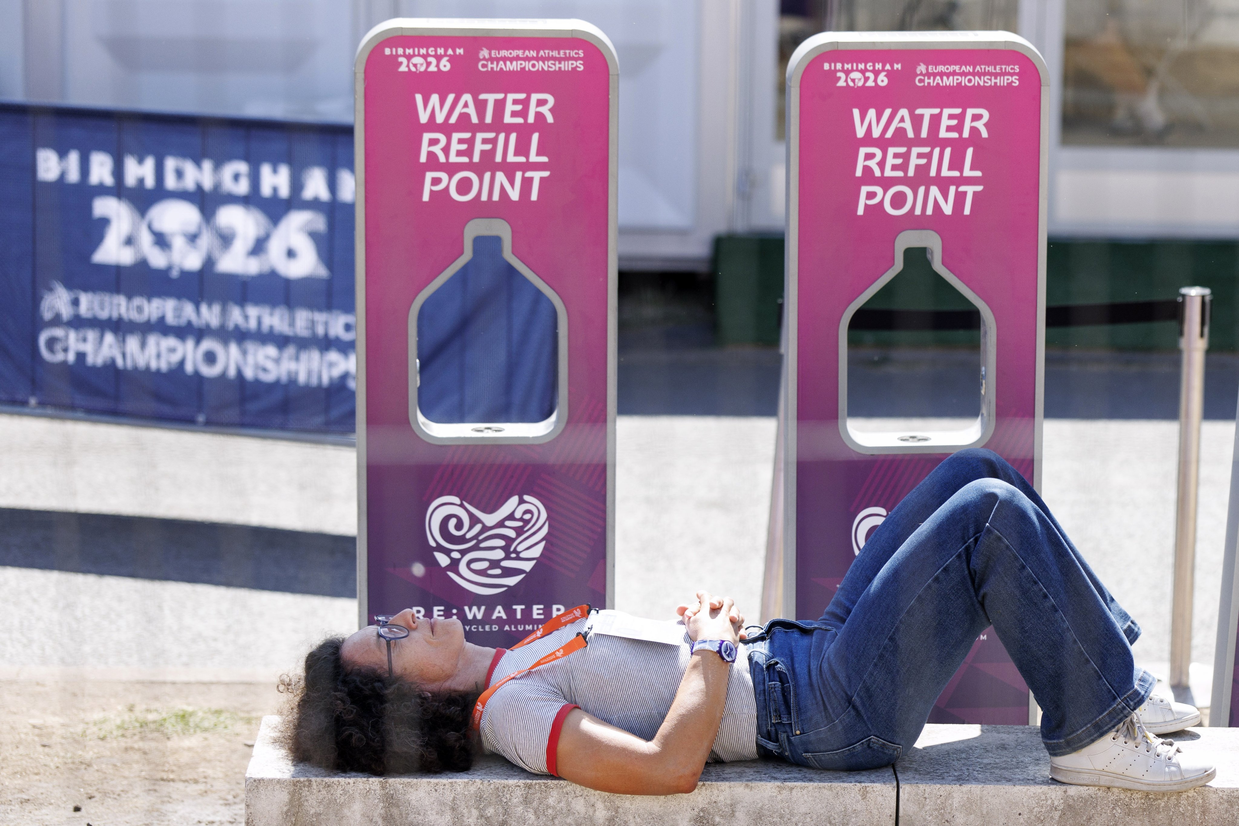 A person lying next to water refill points at the European Athletics Championships in Birmingham, UK, on Wednesday. An amber weather warning has been issued as another heatwave sweeps across the UK. Photo: EPA