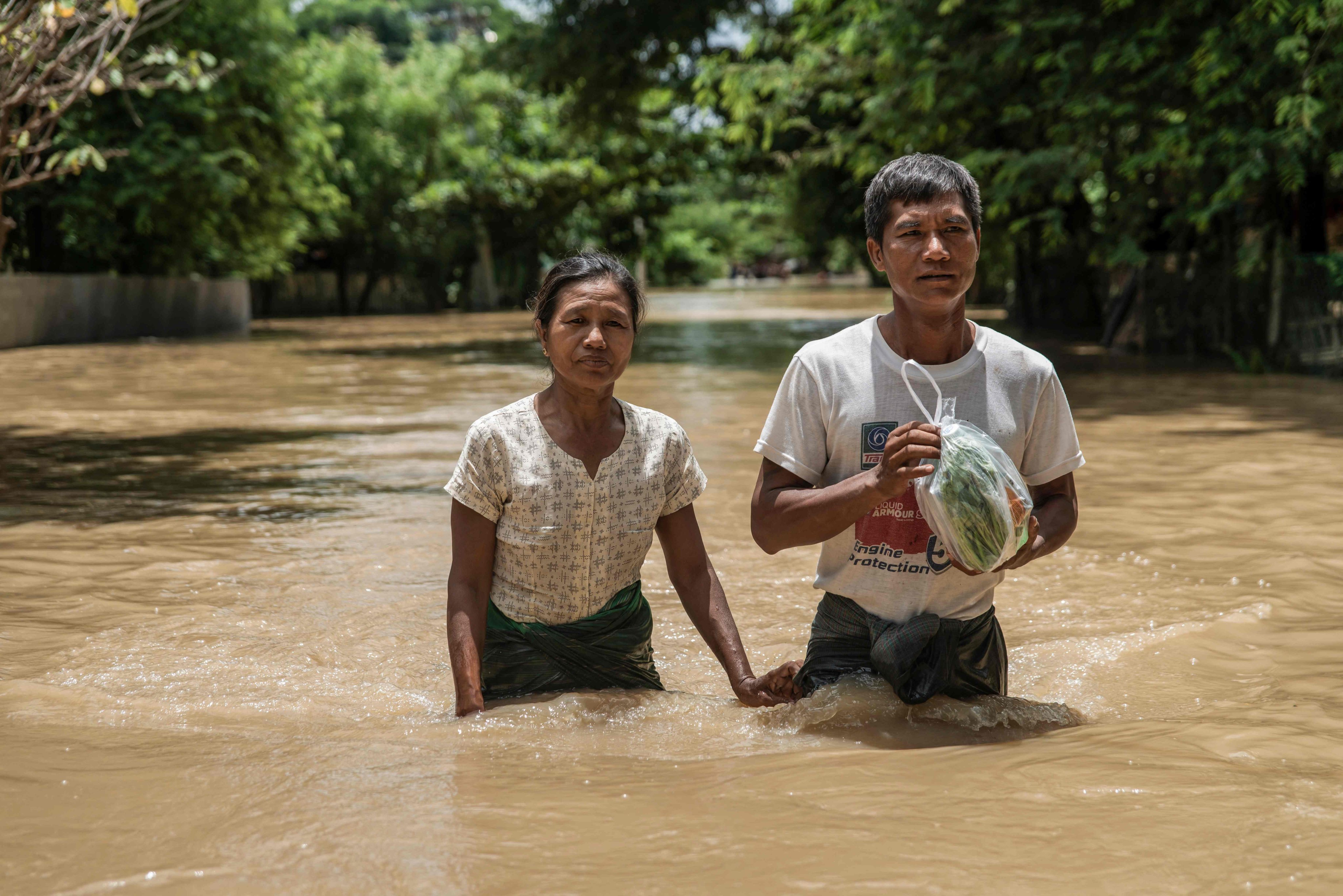 People wade through a flooded area due to monsoon rains and rising river water levels in Wetlet, Myanmar’s Sagaing region on Monday.  Photo: AFP