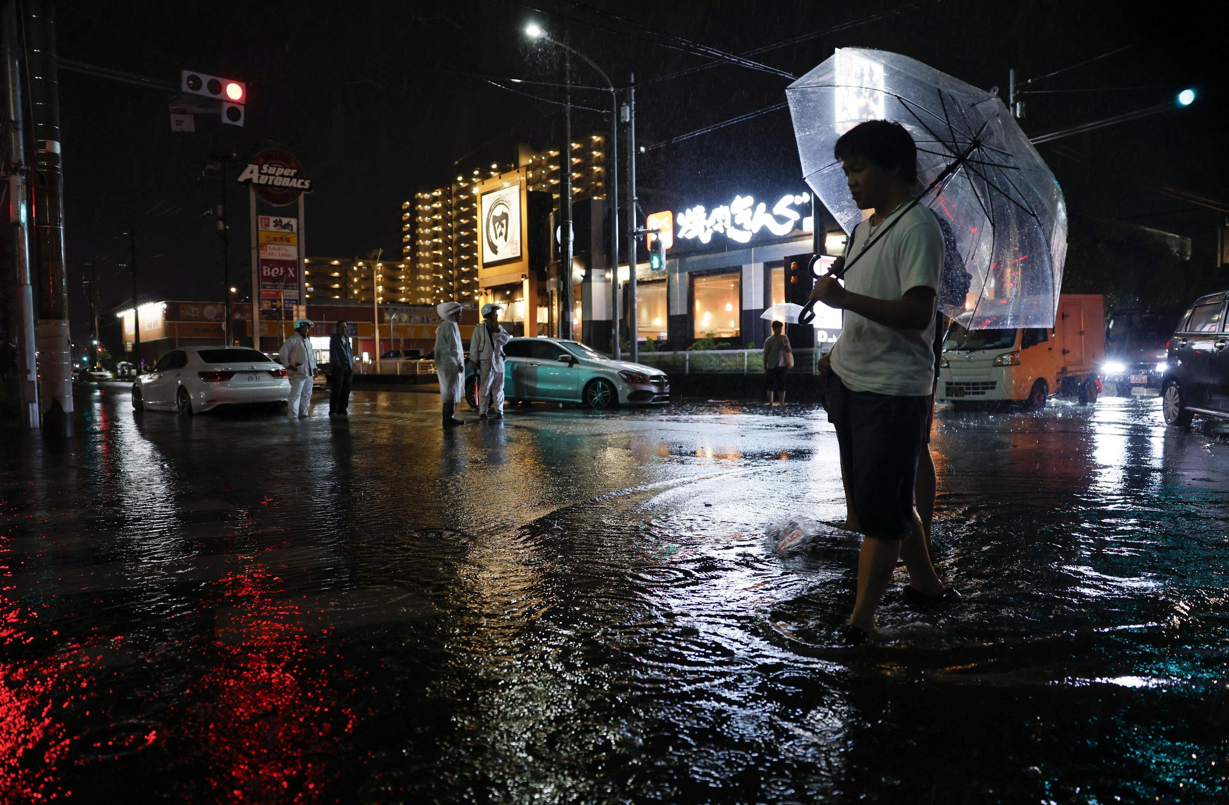A man walks on a flooded road after torrential rain in Ichikawa, Chiba Prefecture, Japan, August 13, 2026. Kyodo/via REUTERS ATTENTION EDITORS - THIS IMAGE WAS PROVIDED BY A THIRD PARTY. EDITORIAL USE ONLY. MANDATORY CREDIT. JAPAN OUT. NO COMMERCIAL OR EDITORIAL SALES IN JAPAN.