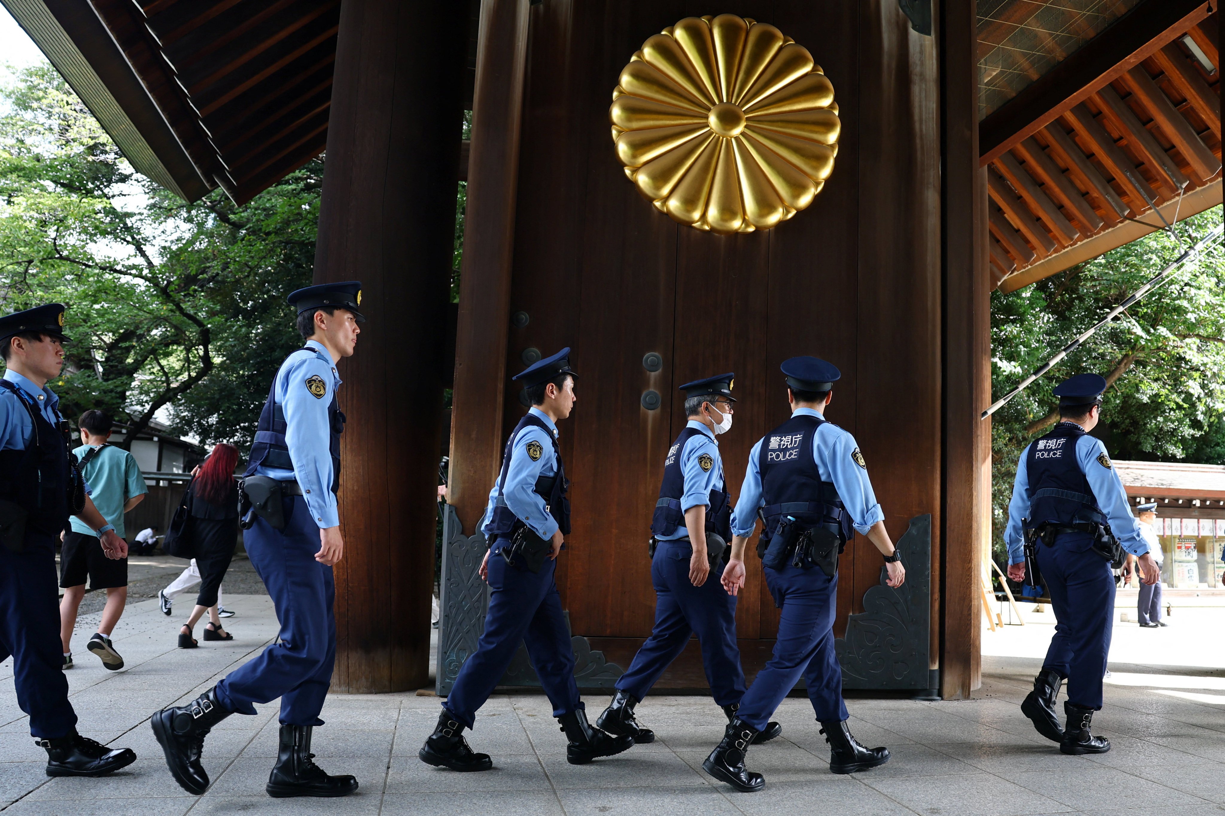 Police officers walk in line as people visit to pay tribute to the war dead at Yasukuni Shrine in Tokyo on Saturday on the 81st anniversary of Japan’s surrender in World War II. Photo: Reuters