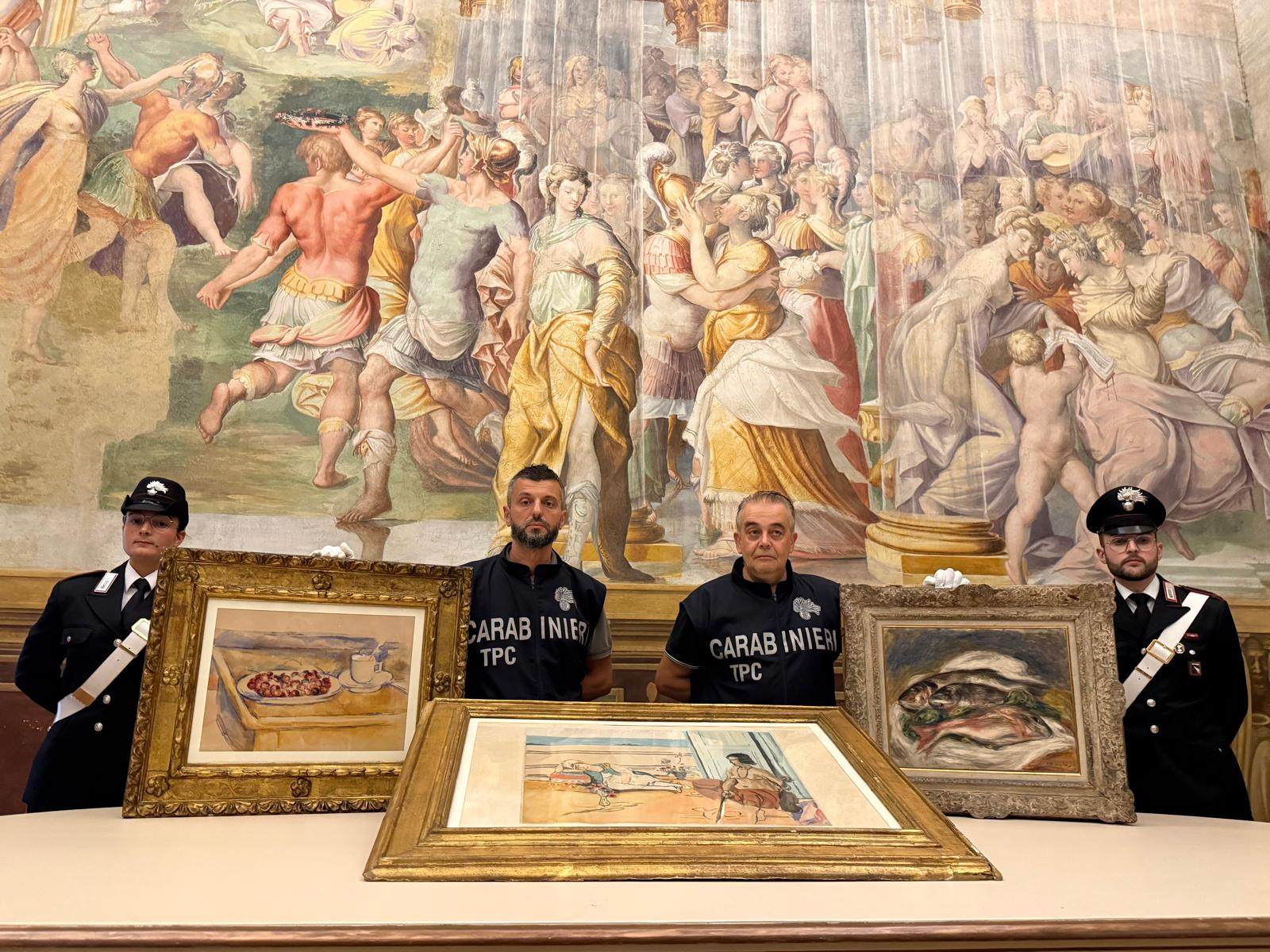 Italian Carabinieri officers pose with three artworks recovered following a police operation, in an image released on Friday. Photo: Italian Carabinieri via AP