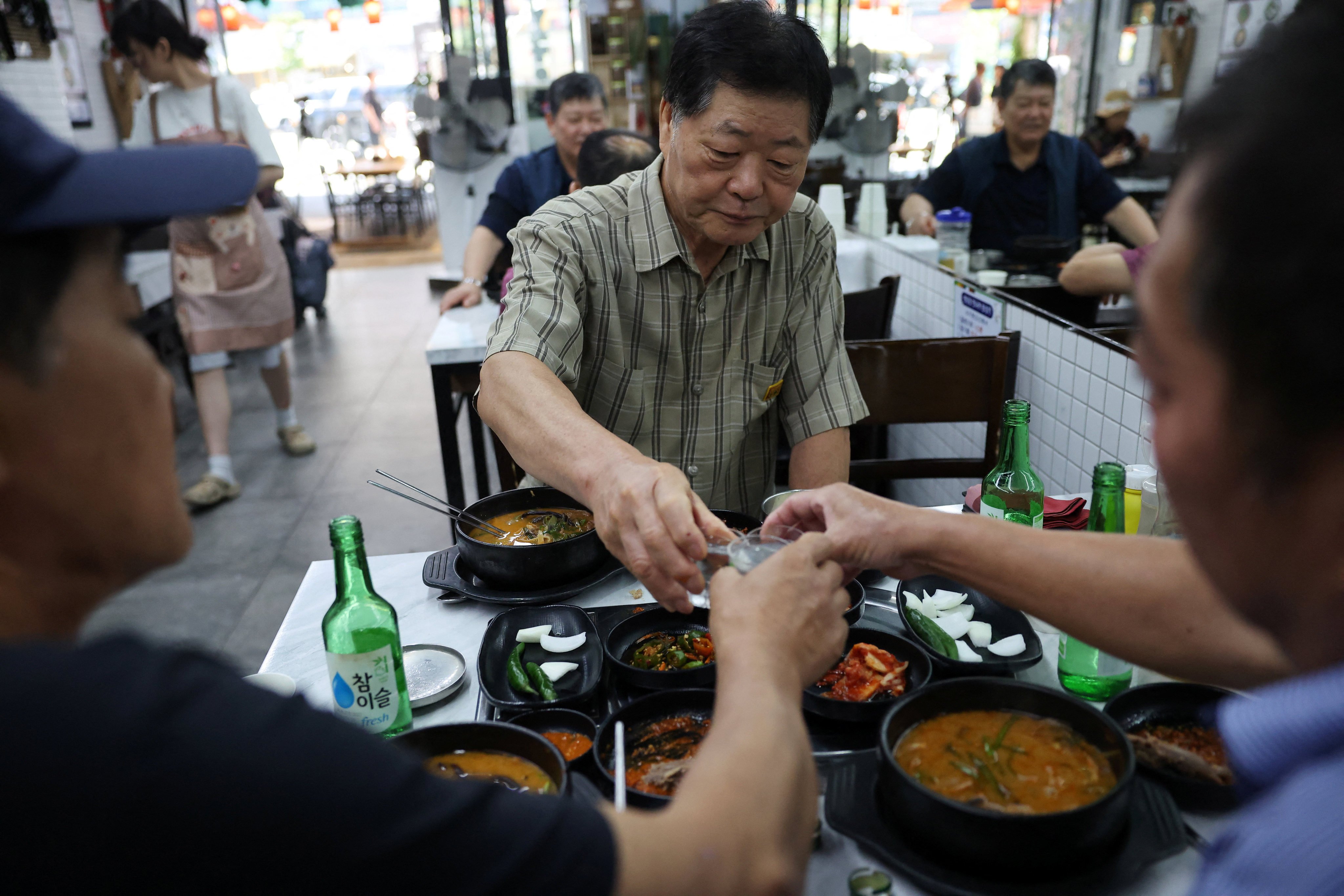 South Koreans toast as they eat dog meat stews during Malbok, the last of Korea’s traditional hottest days of summer, at a restaurant selling dog meat and black goat meat stews in Seongnam, South Korea on Friday.   Photo: Reuters