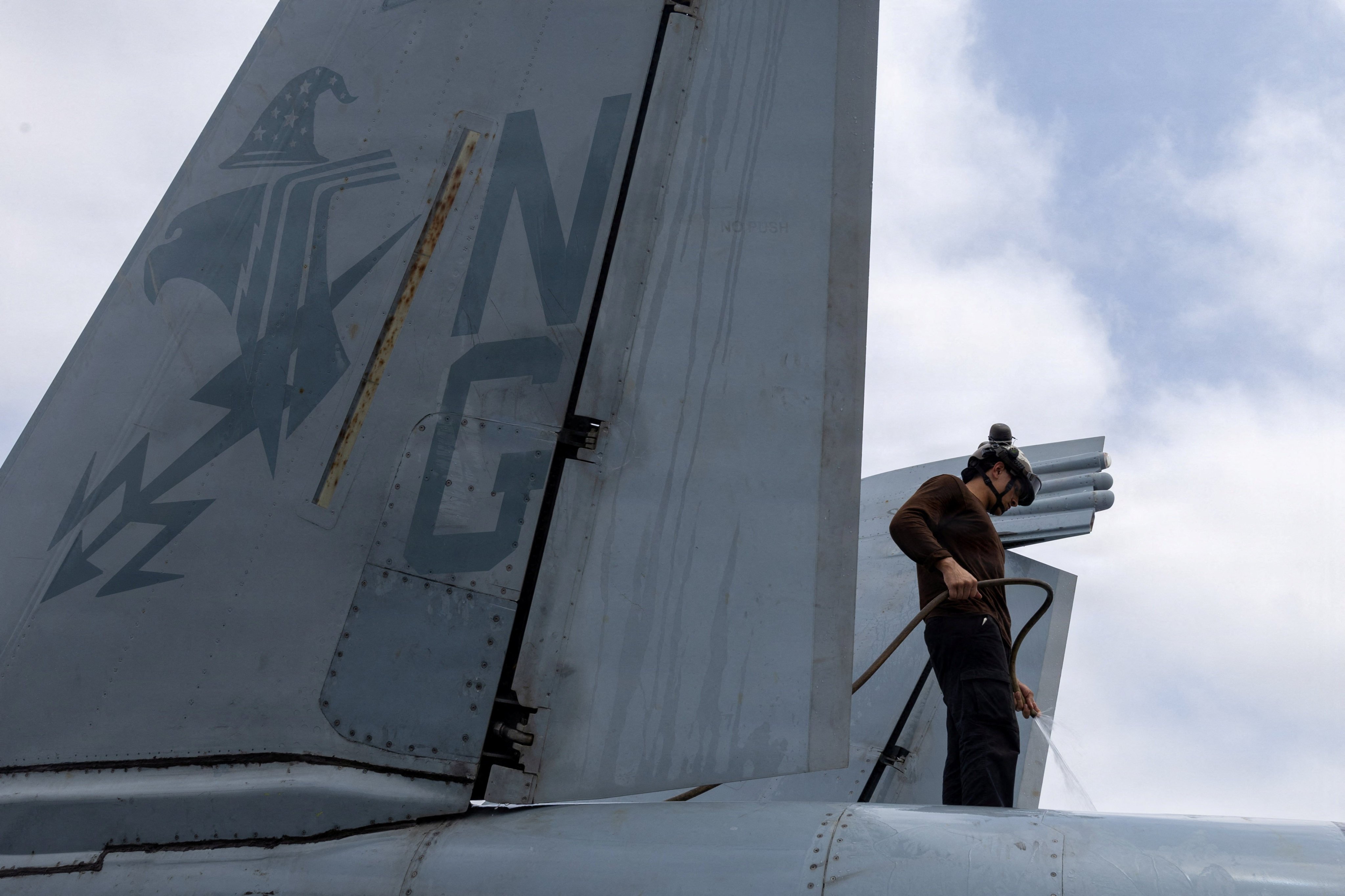 A U. sailor washes an EA-18G Growler on the flight deck of the USS Abraham Lincoln on August 9.  Photo: US Navy/Reuters