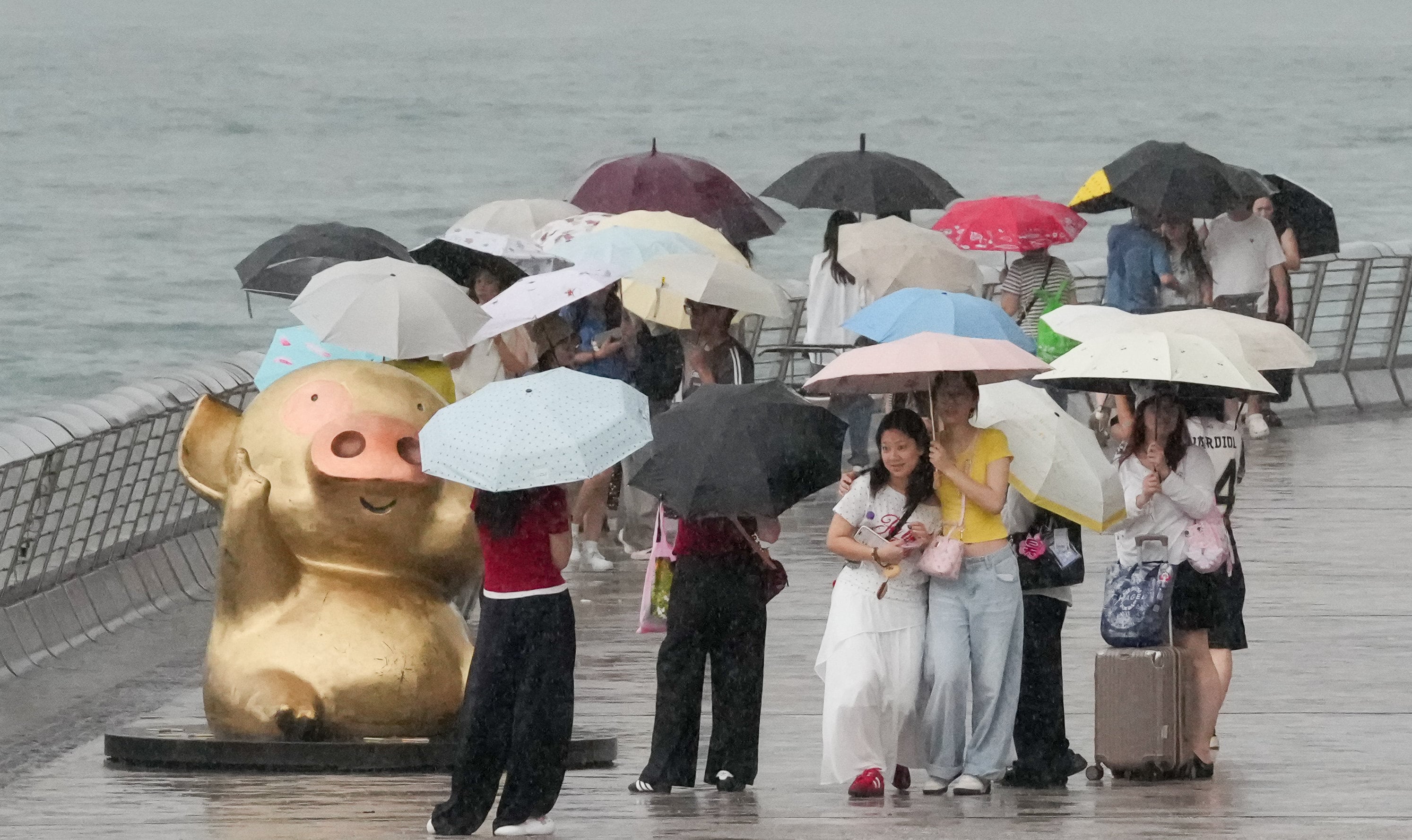 Tourists brave the rain at the Tsim Sha Tsui waterfront. Photo: Jelly Tse