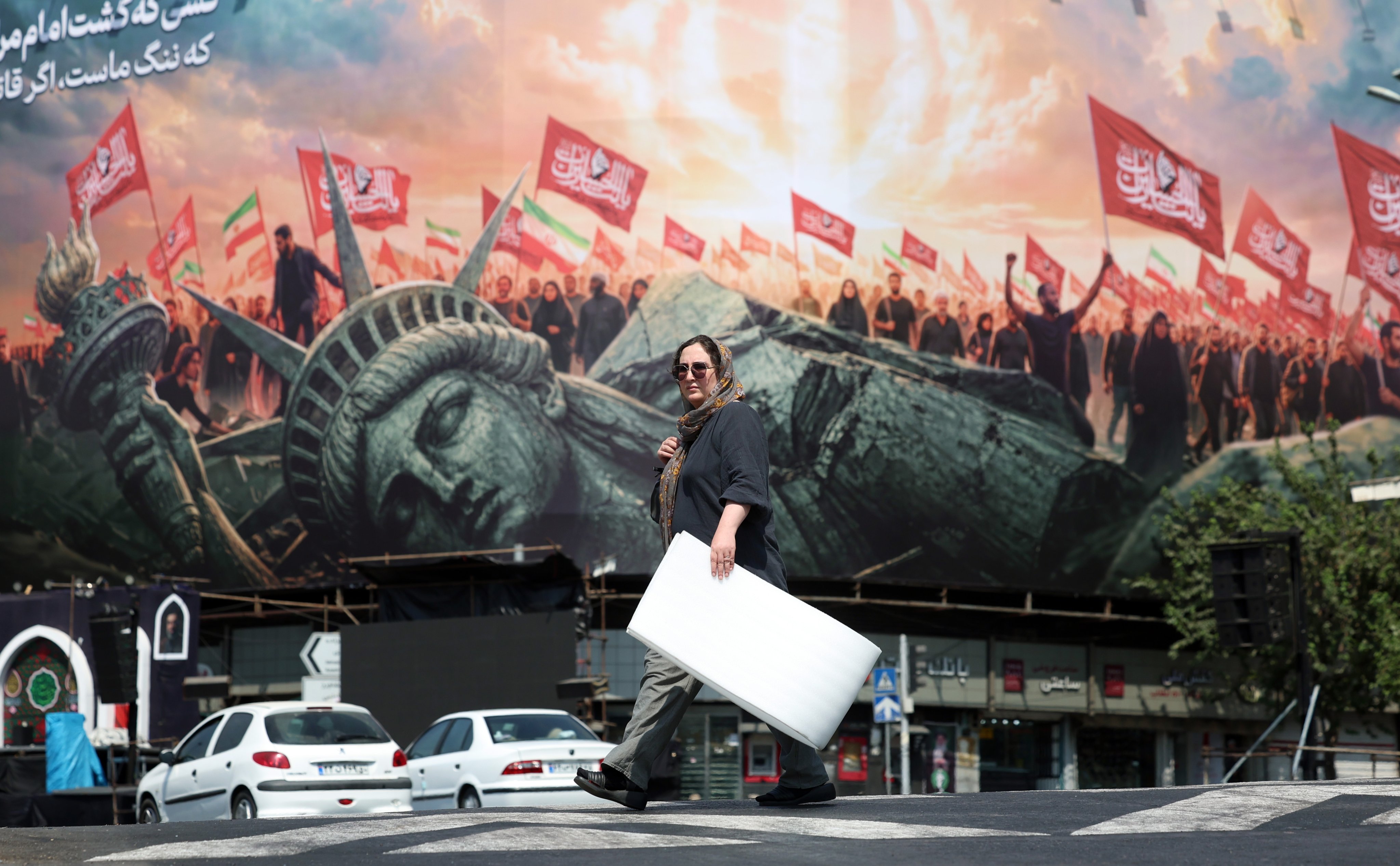 An Iranian woman walks next to an anti-US sign at Enghelab square in central Tehran, Iran on Thursday. Photo: EPA