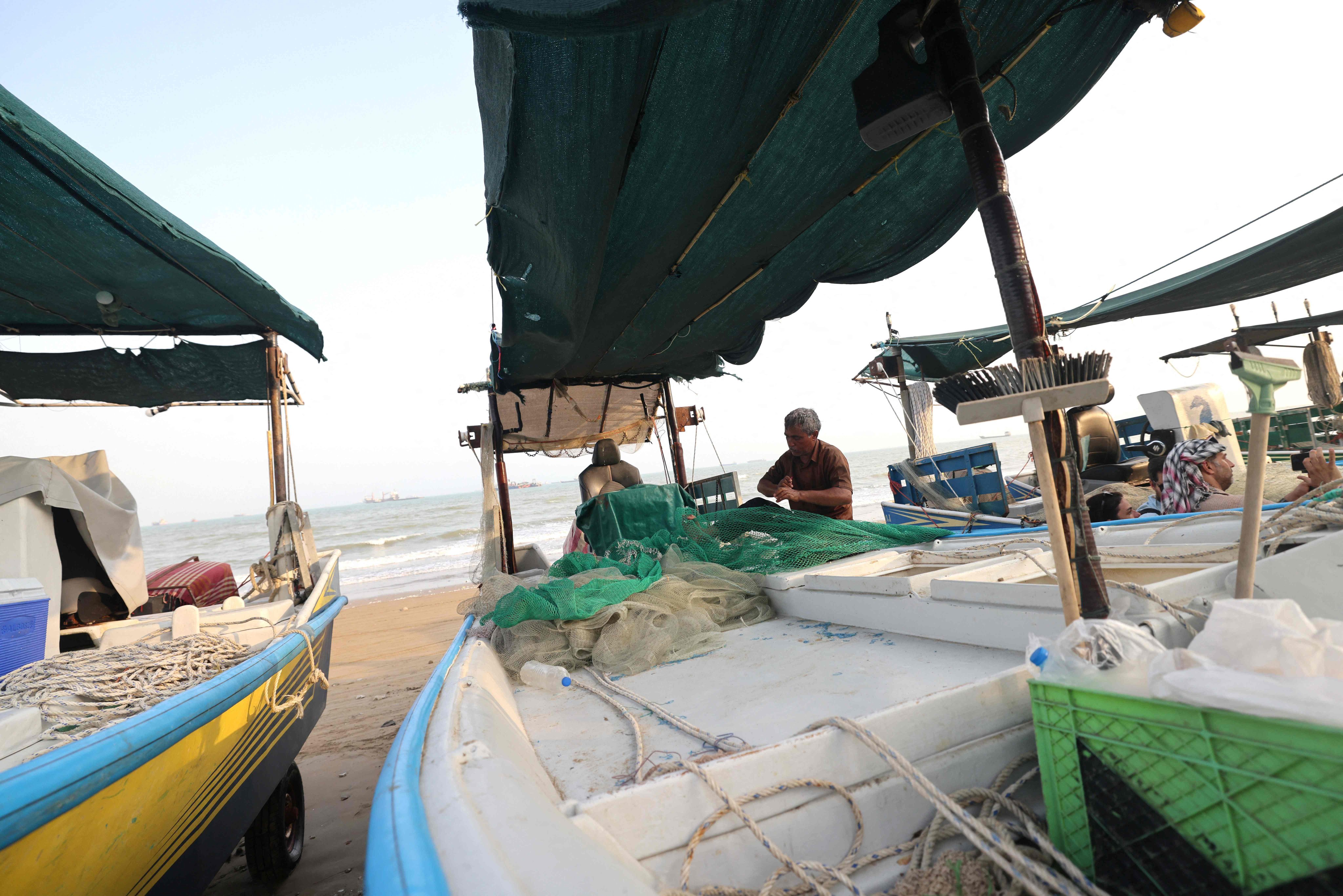 Fishermen check their nets and small boats on the seashore in the Iranian port city of Bandar Abbas on August 10. Photo: AFP