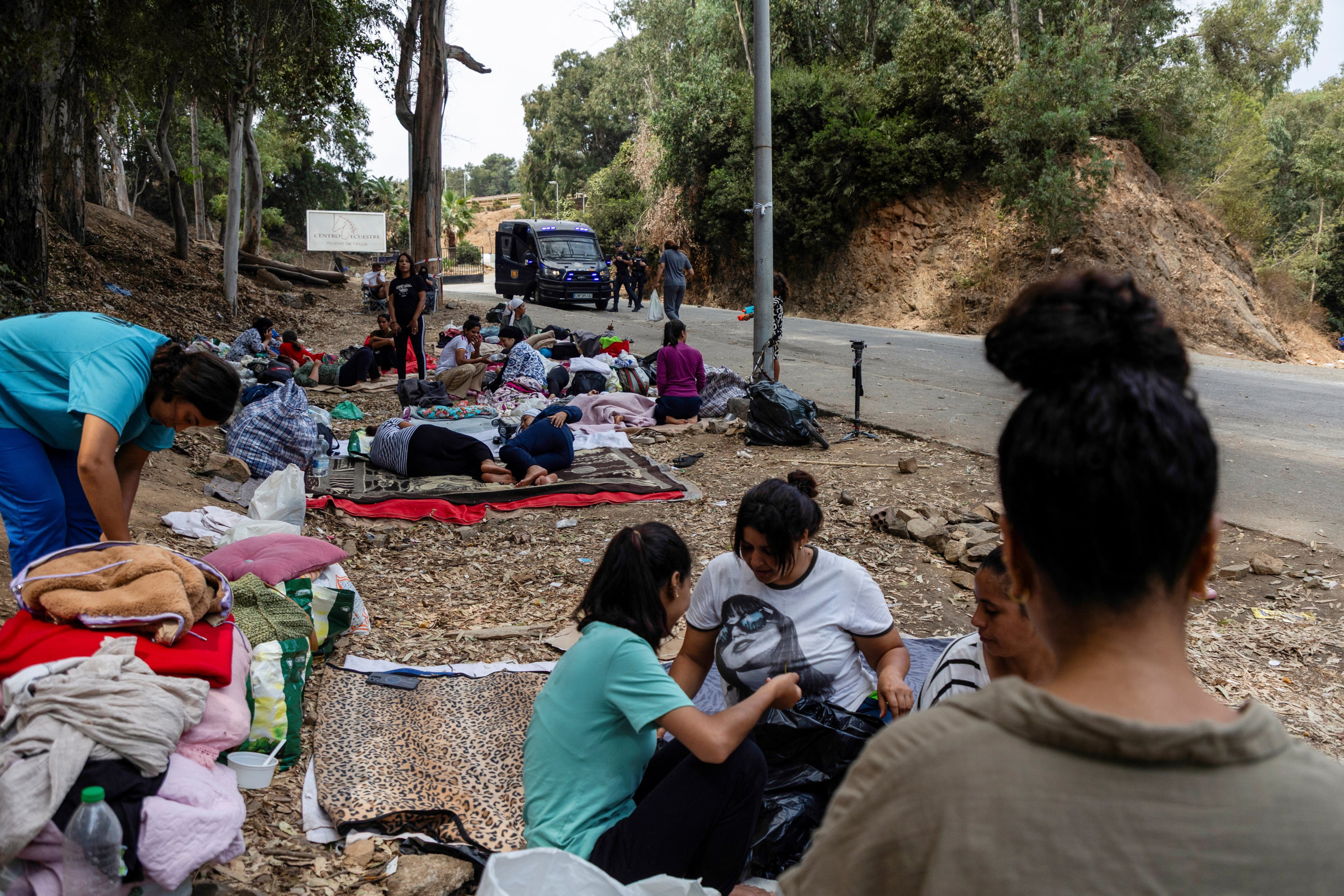 Moroccan women migrants gather with their belongings near the Temporary Immigrant Reception Centre as a police vehicle is seen nearby in Ceuta, Spain, on Sunday. Photo: Reuters