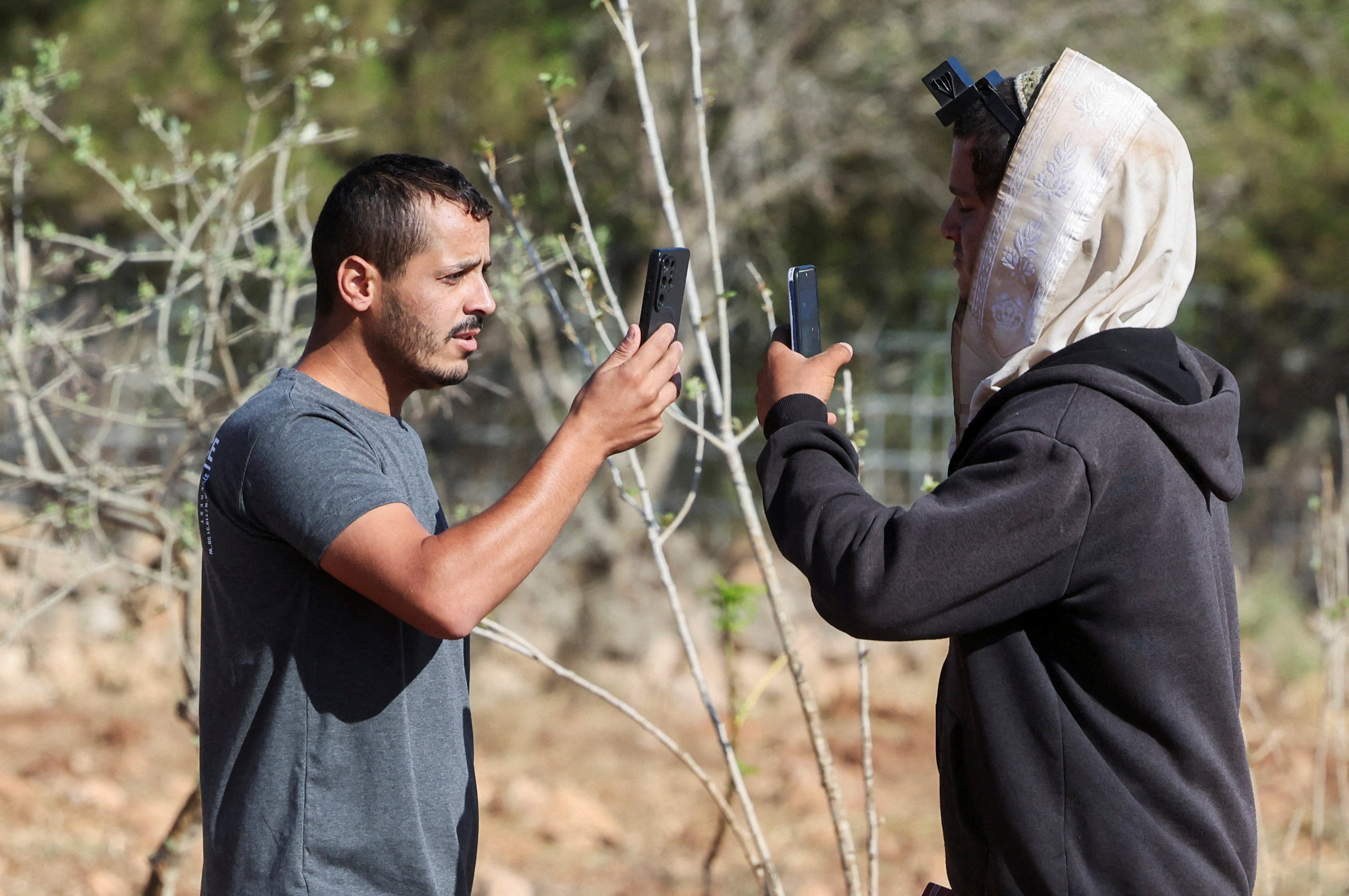 Yousef Hassan (left), whose house was encircled by militant settlers and later taken over by the military, films an Israeli settler (right) who entered the property of Palestinian-American Loui Ridi, in Qusra, Israeli-occupied West Bank, on Tuesday. Photo: Reuters