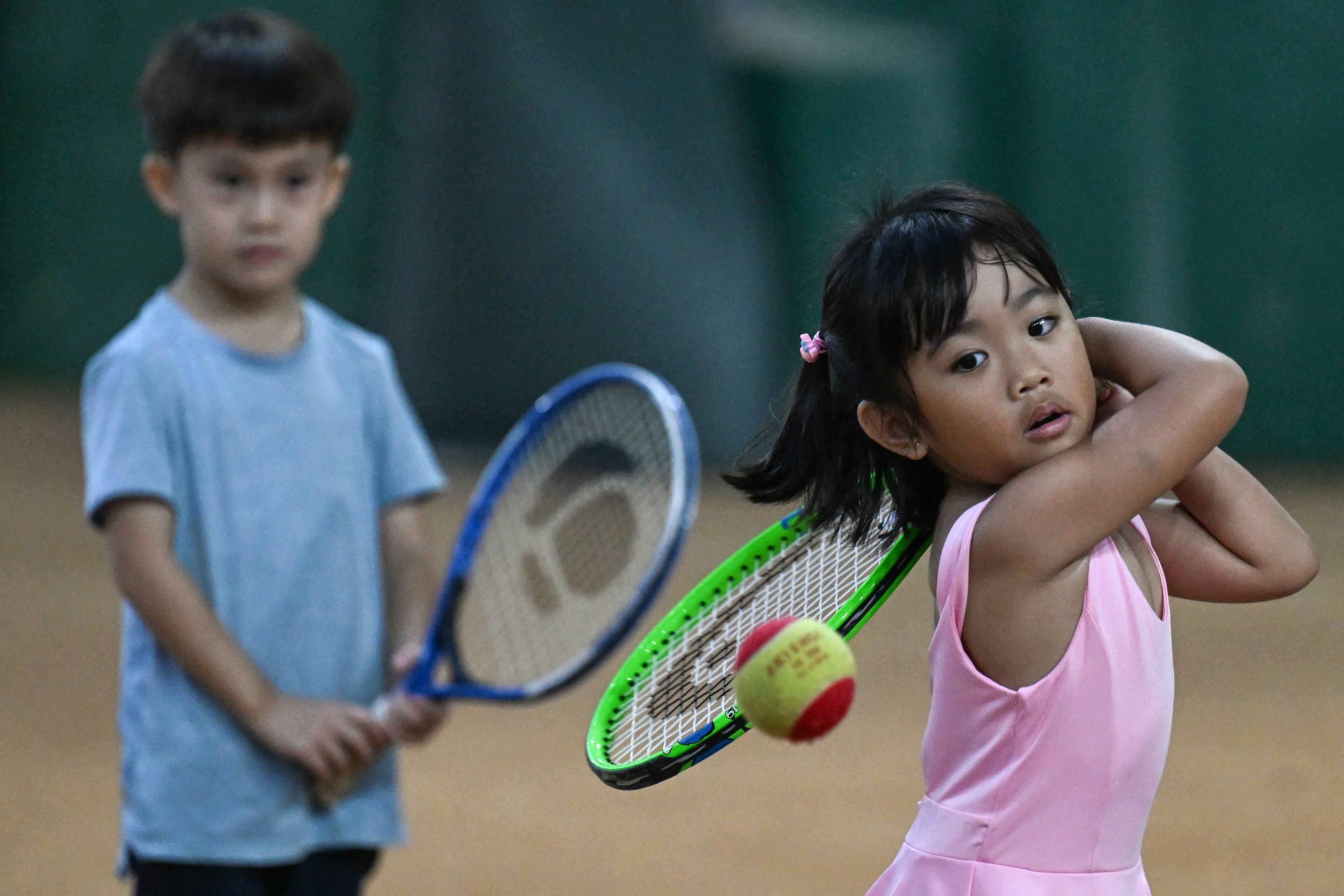 This photo taken on August 7, 2026, shows children taking part in a training session at Alabang Tennis Academy in Muntinlupa, Metro Manila. On a Manila court made of crushed seashells, an earnest four-year-old sends a forehand sailing wide - one of dozens of kids aiming to follow in the footsteps of the Philippine’s first homegrown tennis sensation, Alex Eala. (Photo by Jam STA ROSA / AFP) / To go with ‘TENNIS-PHILIPPINES-EALA,FOCUS’ by Cecil MORELLA