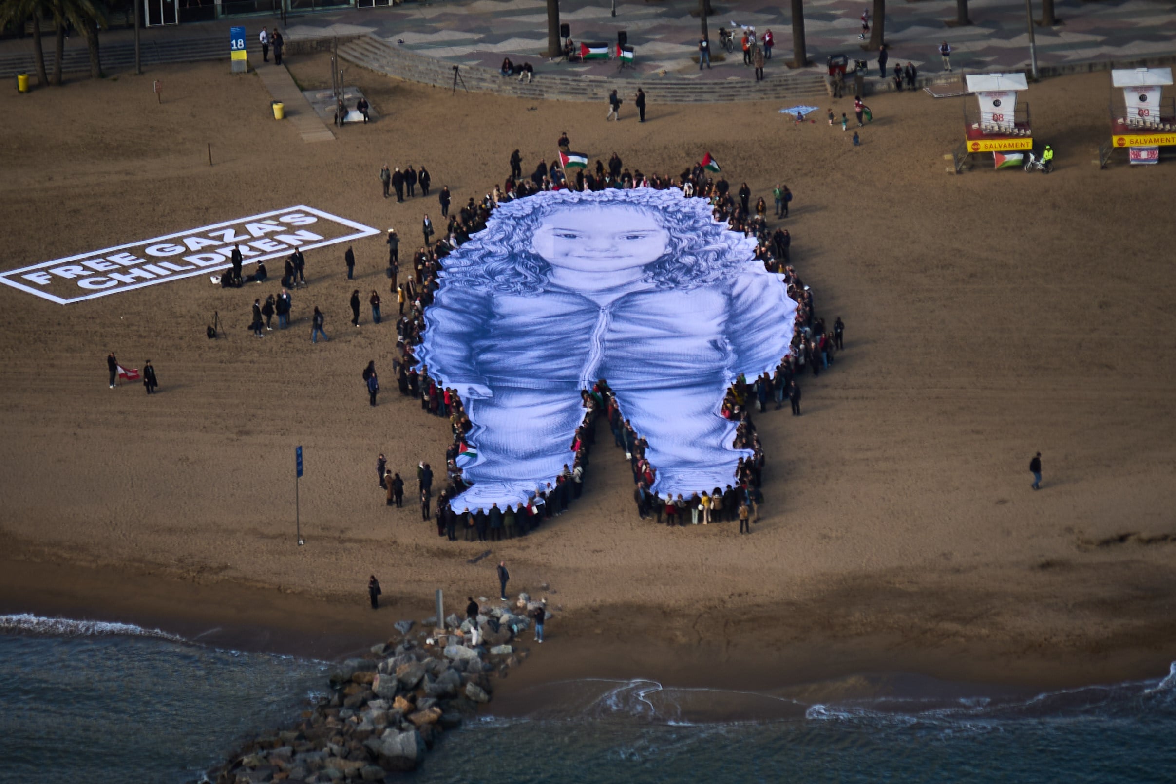 People hold a giant portrait of Hind Rajab, a five-year-old Palestinian girl who was killed during the war in Gaza, on a beach in Barcelona, Spain, in January. Photo: AP