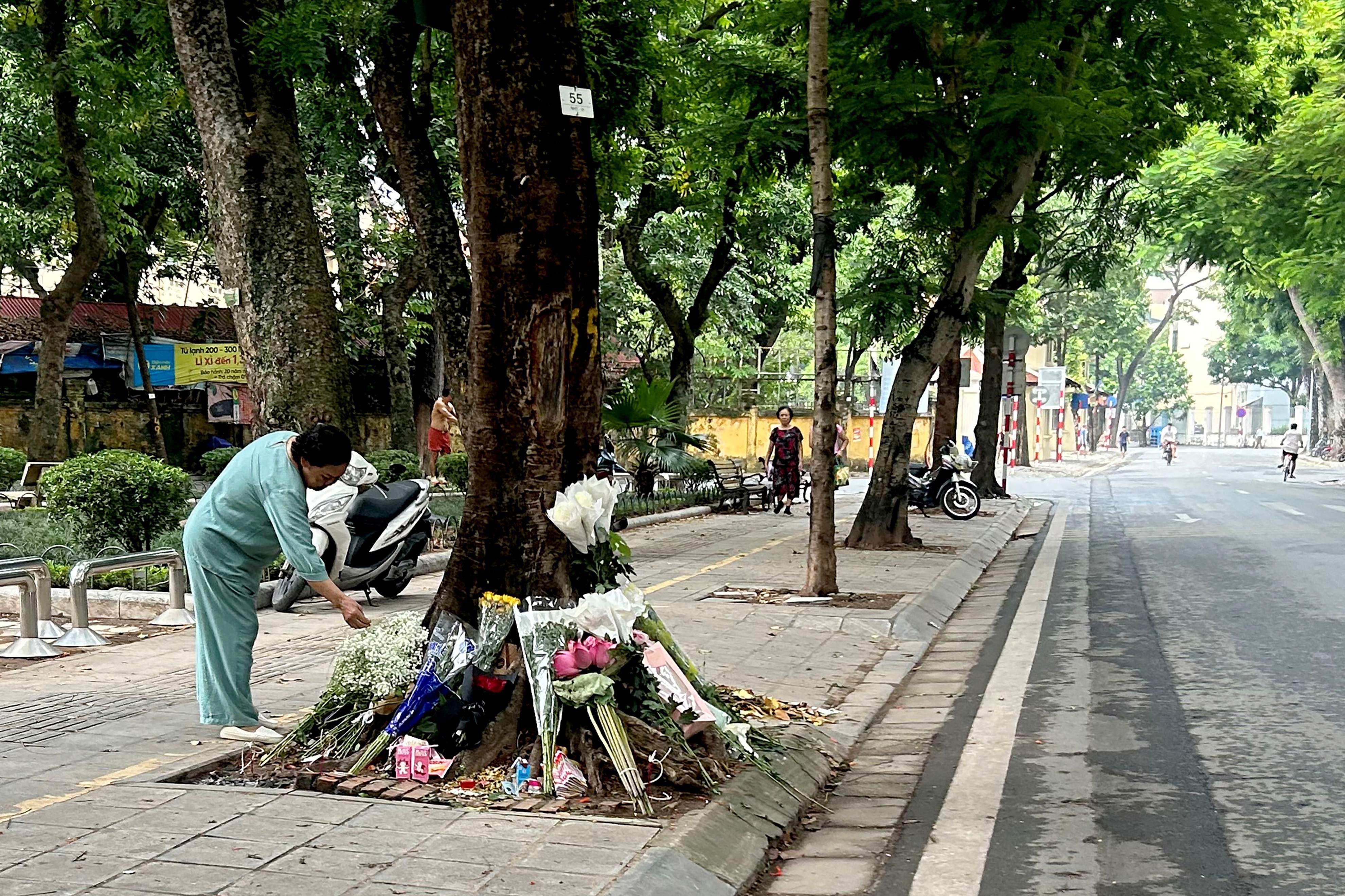 A woman looks at flowers placed on Saturday at the site of a traffic accident where a senior official had a fatal car crash in Hanoi. Photo: AFP
