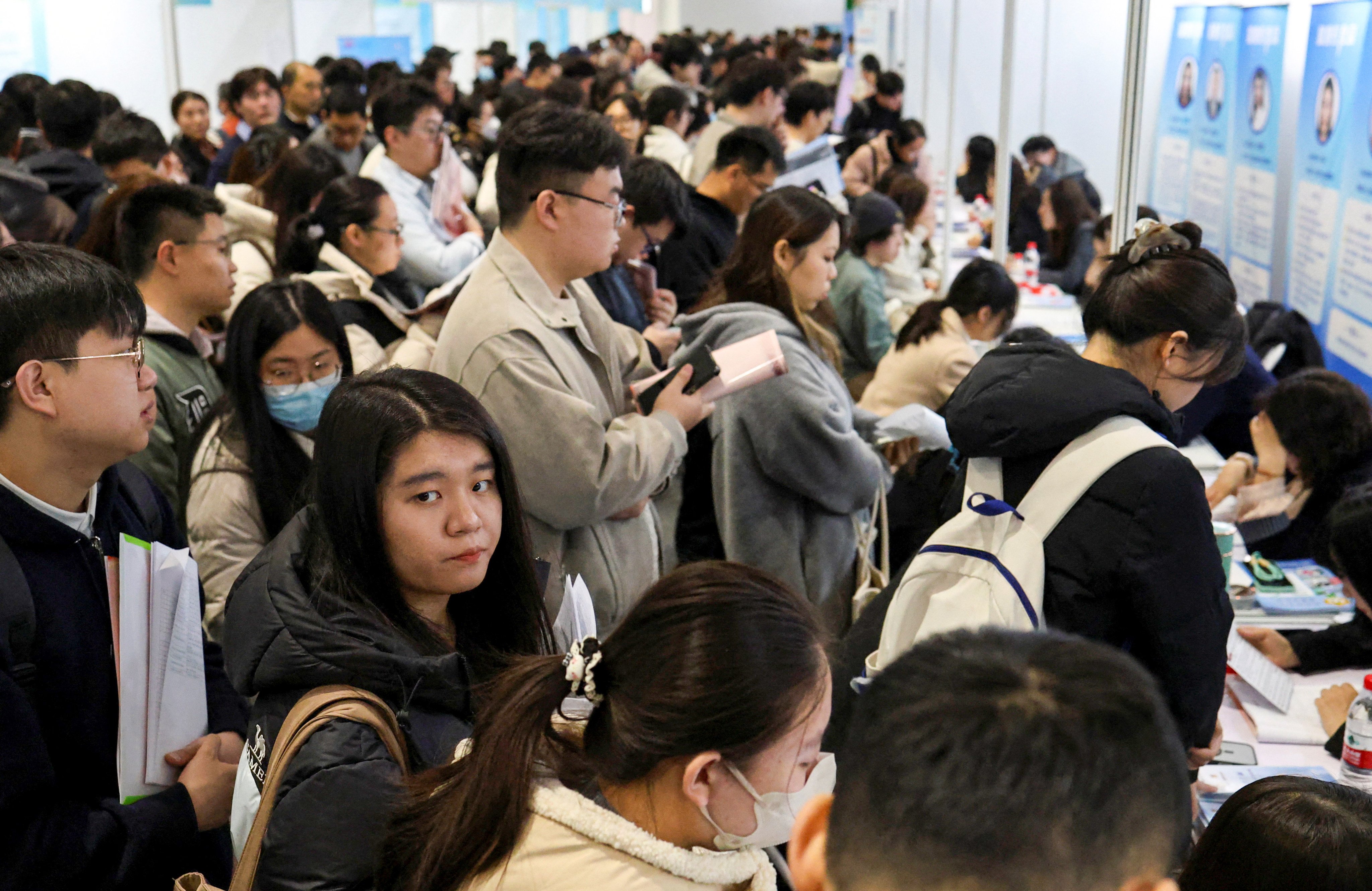 People line up at career guidance booths at a job fair in Beijing in March. Photo: Reuters