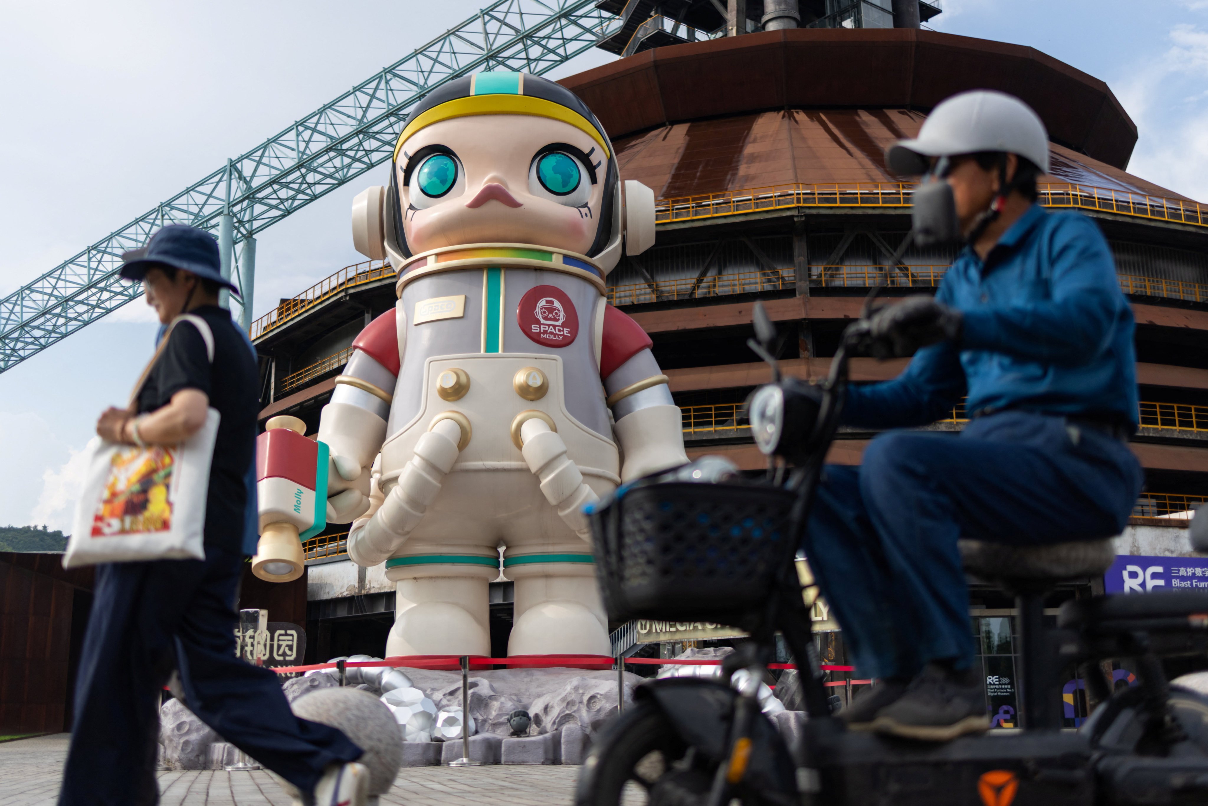 People pass by a giant figure of the Pop Mart character Space Molly in Beijing’s Shougang Park on August 7. Photo: Reuters