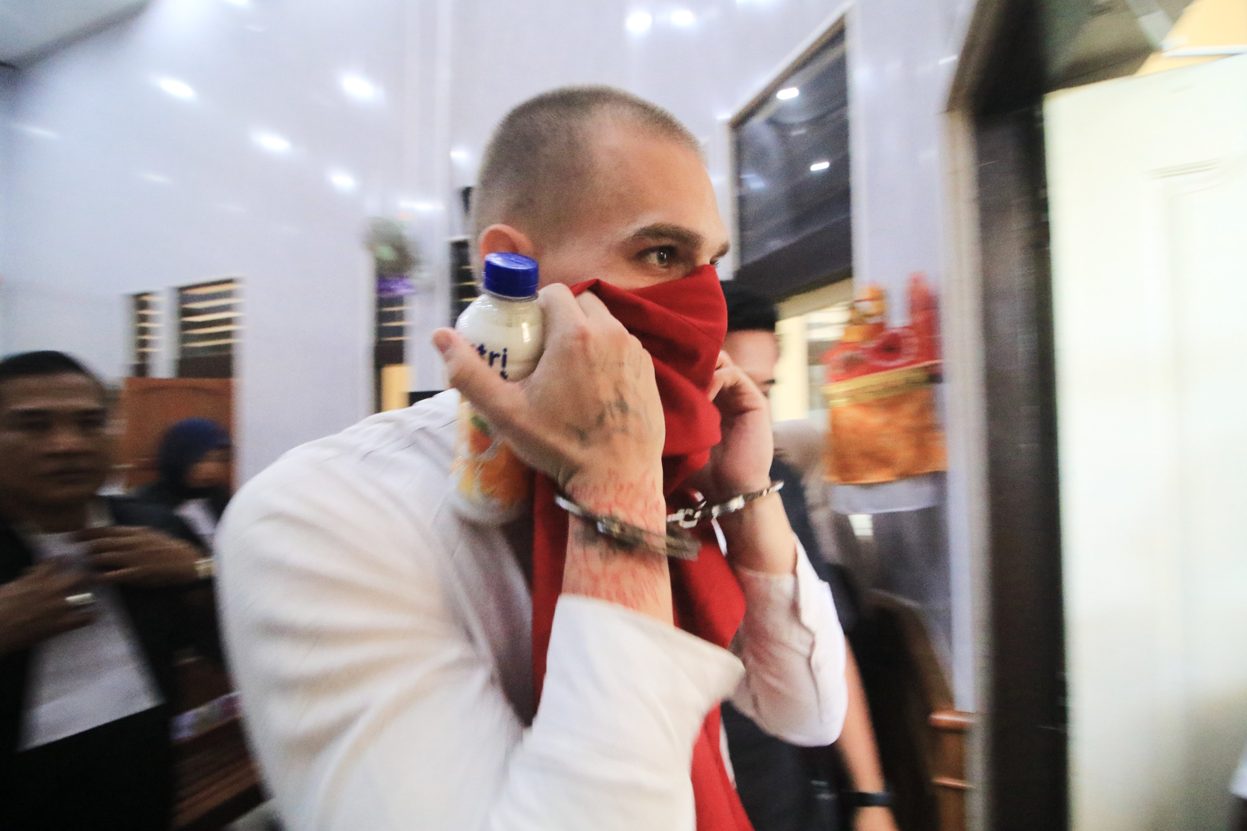 Swiss tourist Luzian Andrin Zgraggen covers his face as he leaves the courtroom after his sentencing hearing at the district court in Denpasar, Bali, Indonesia on Thursday. Photo: AP
