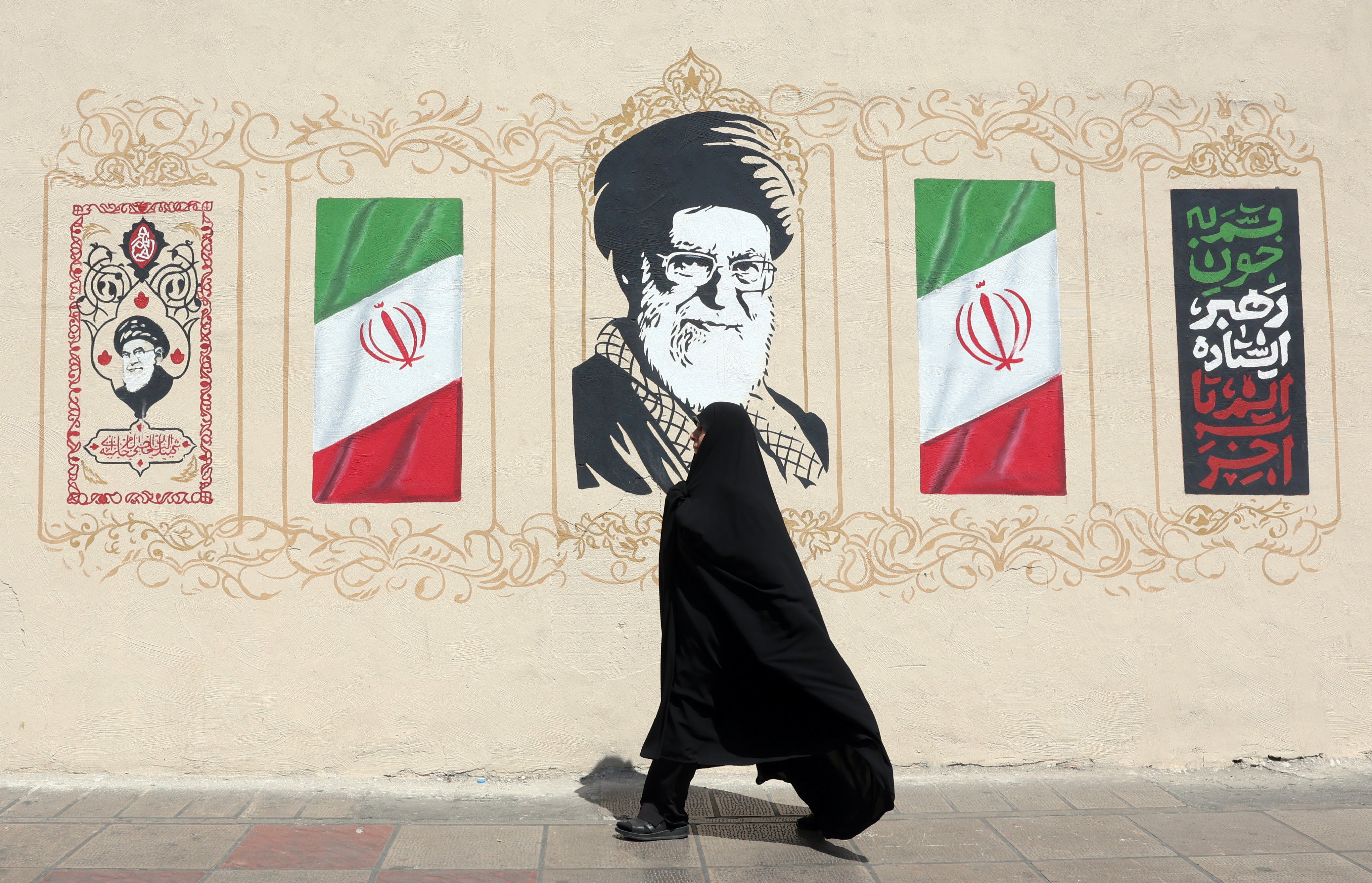 A woman walks next to a wall painting depicting the late Iranian supreme leader Ayatollah Ali Khamenei in Tehran, Iran, on Wednesday. Photo: EPA