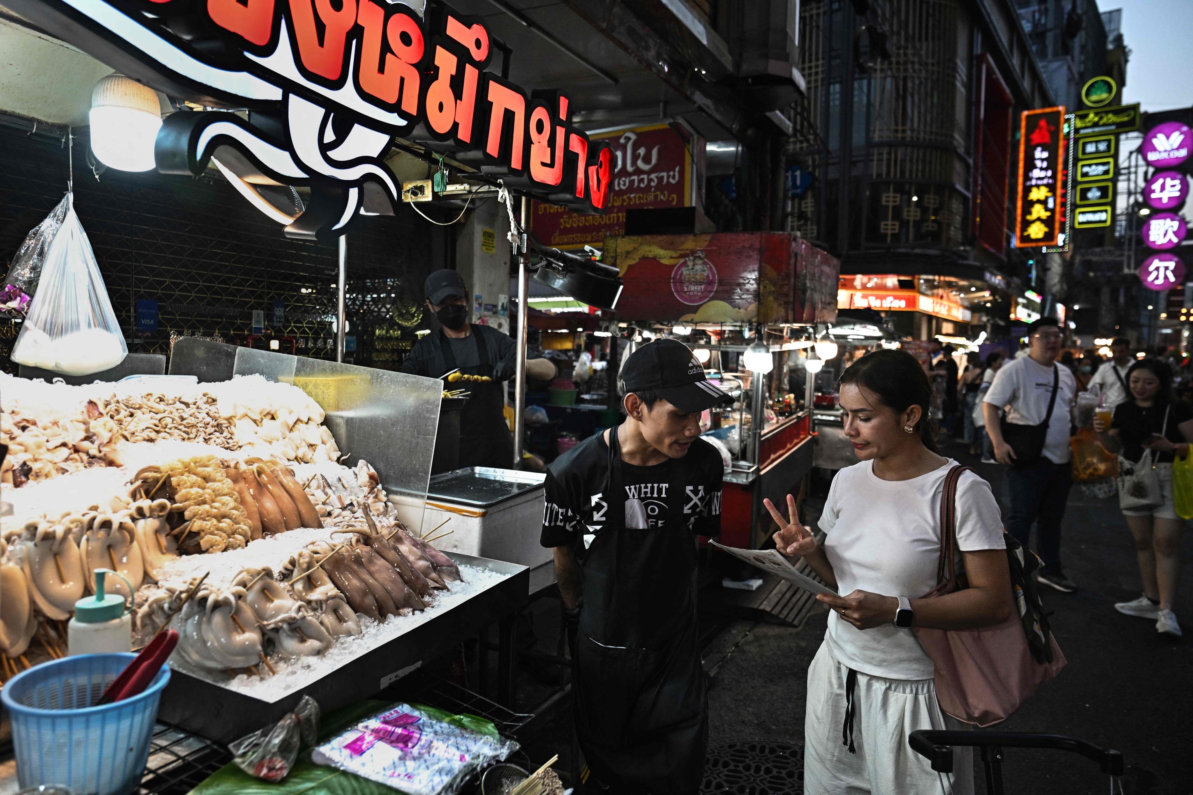A woman orders grilled seafood from a street vendors in Chinatown, Bangkok, on April 29. Photo: AFP