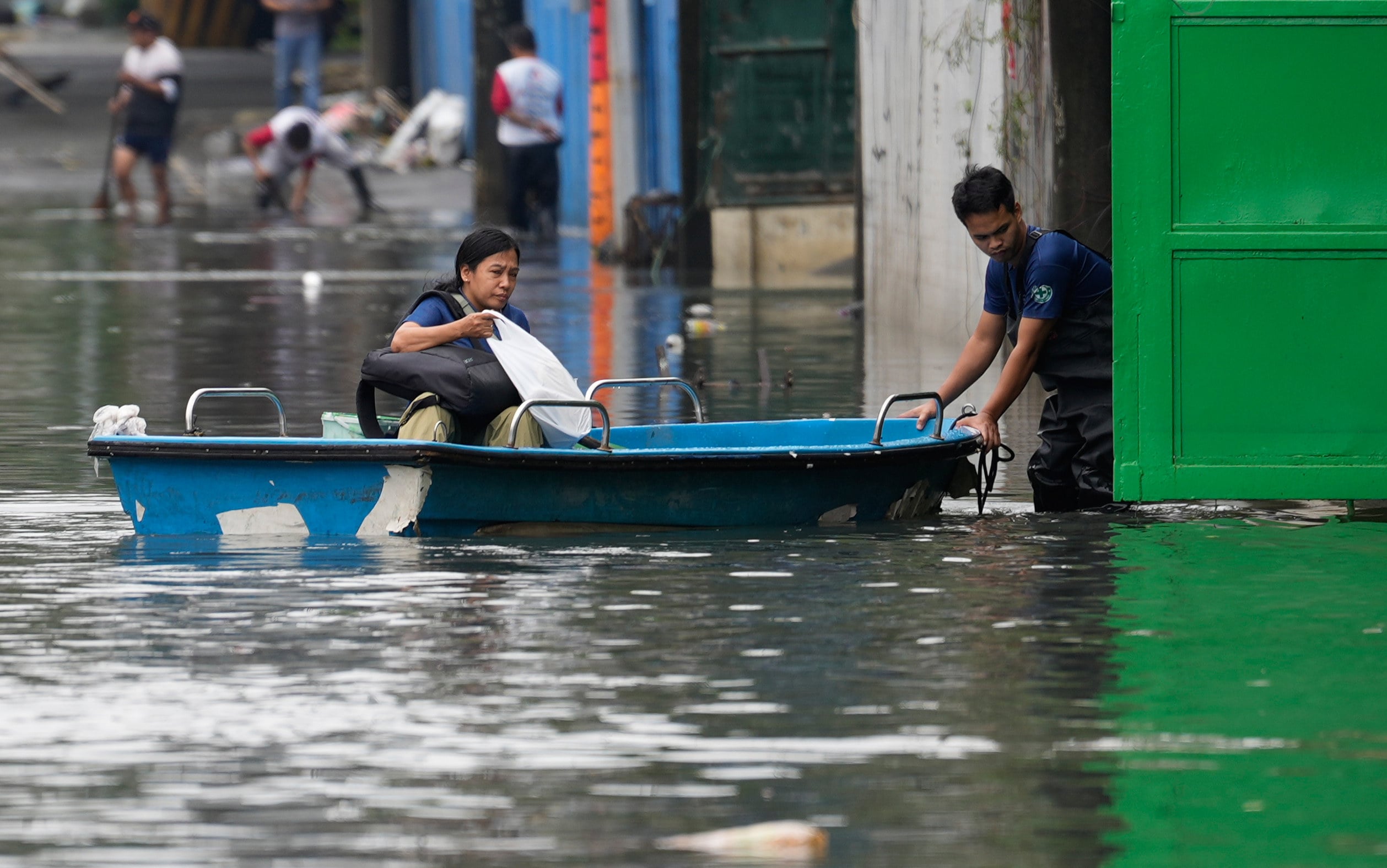 A woman rides a small boat to cross floodwaters caused by intense monsoon rains in Quezon City, Metro Manila, Philippines, on Wednesday. Photo: AP