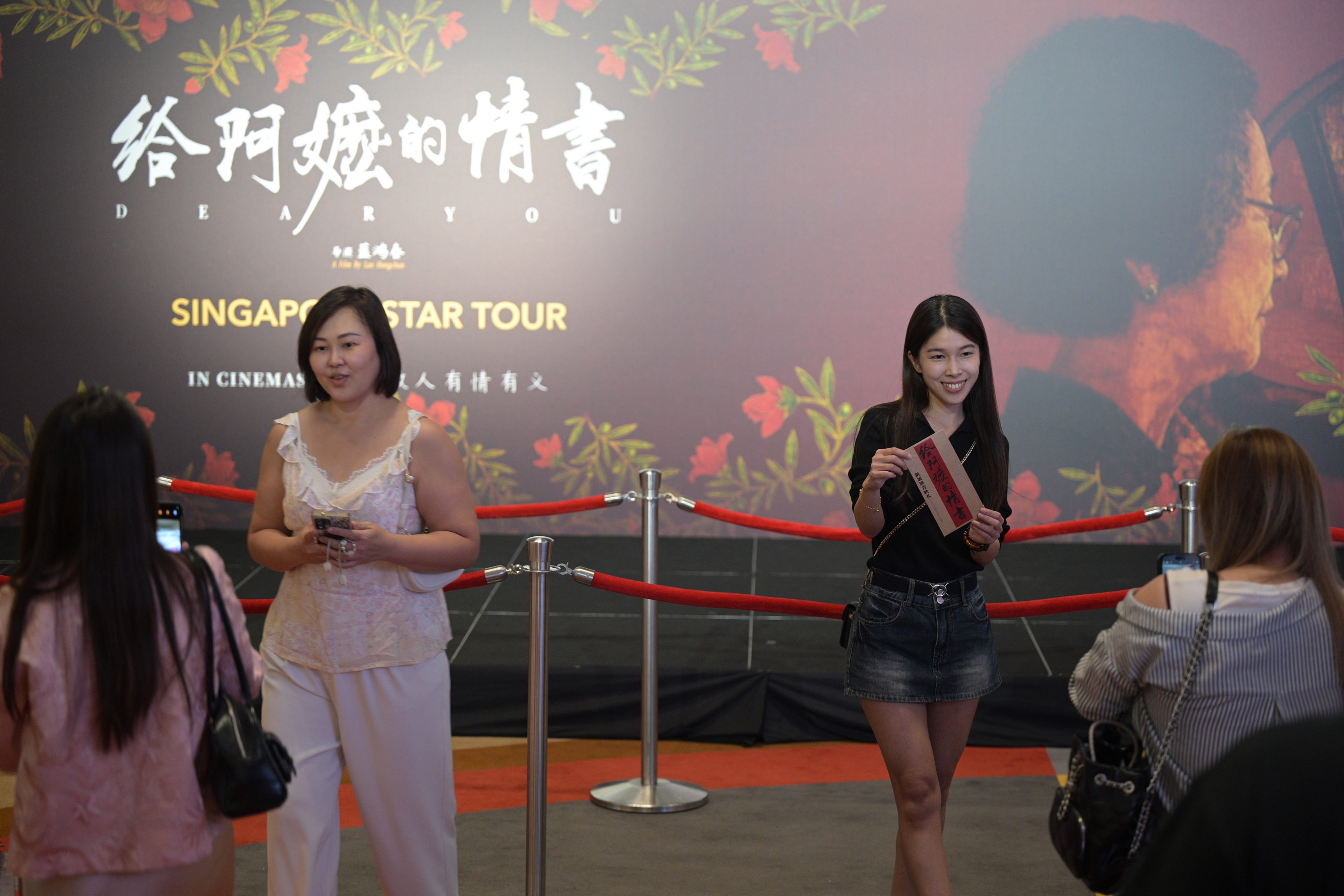 People take photos with a billboard of the Chinese film “Dear You” during its premiere in Singapore on June 17. Photo: Xinhua