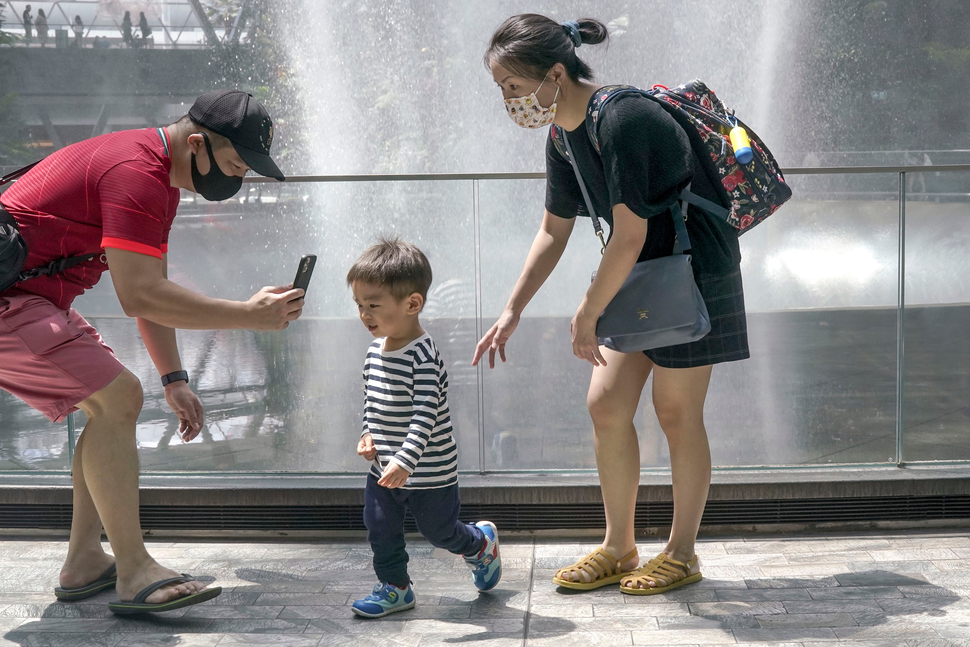 A young child with his parents in front of the Rain Vortex waterfall inside the Jewel Changi Airport mall in Singapore. Photo: EPA-EFE
