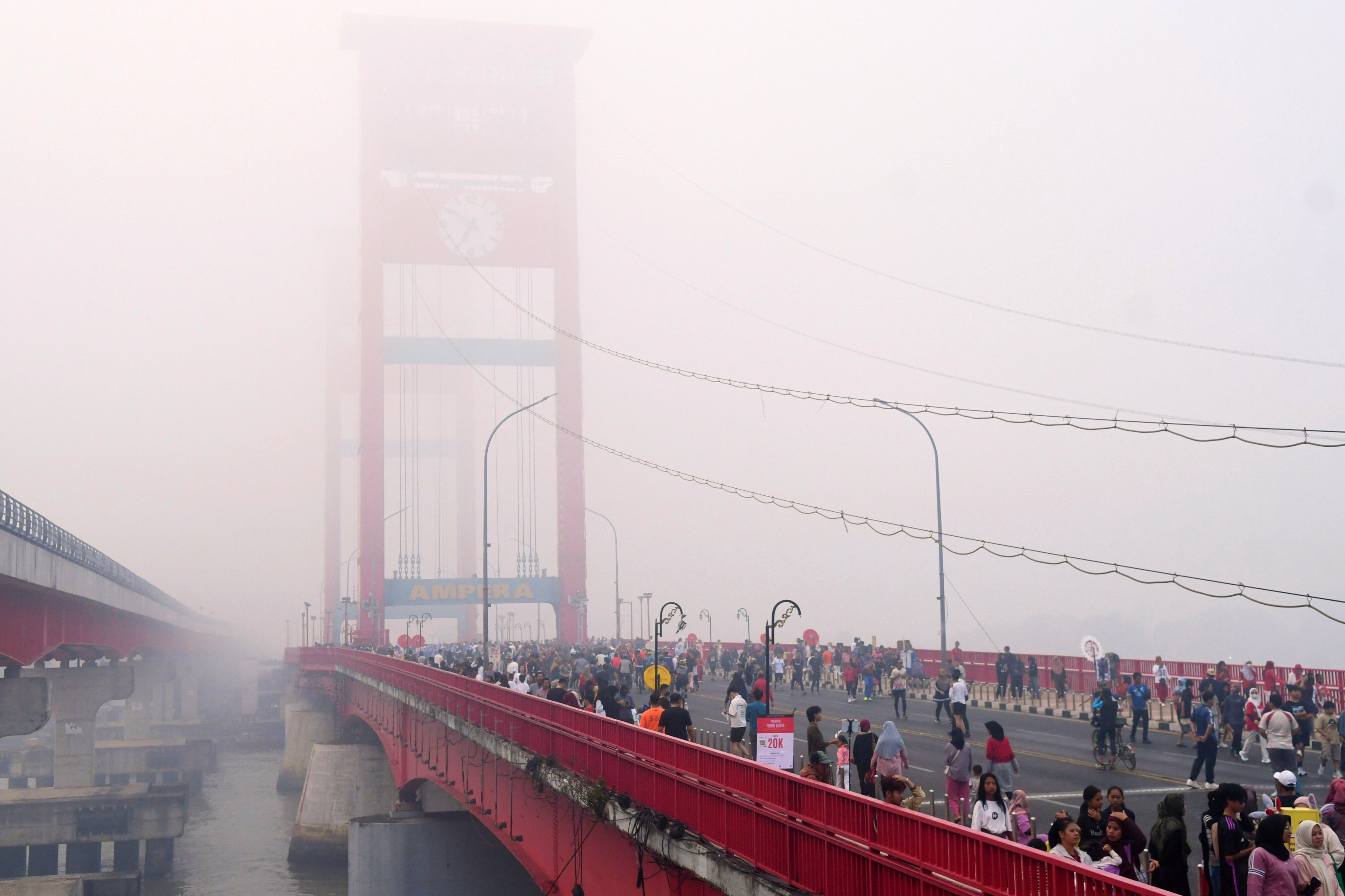 People walk along the Ampera Bridge as haze from wildfires blankets the city of Palembang in South Sumatra on Sunday. Photo: AP