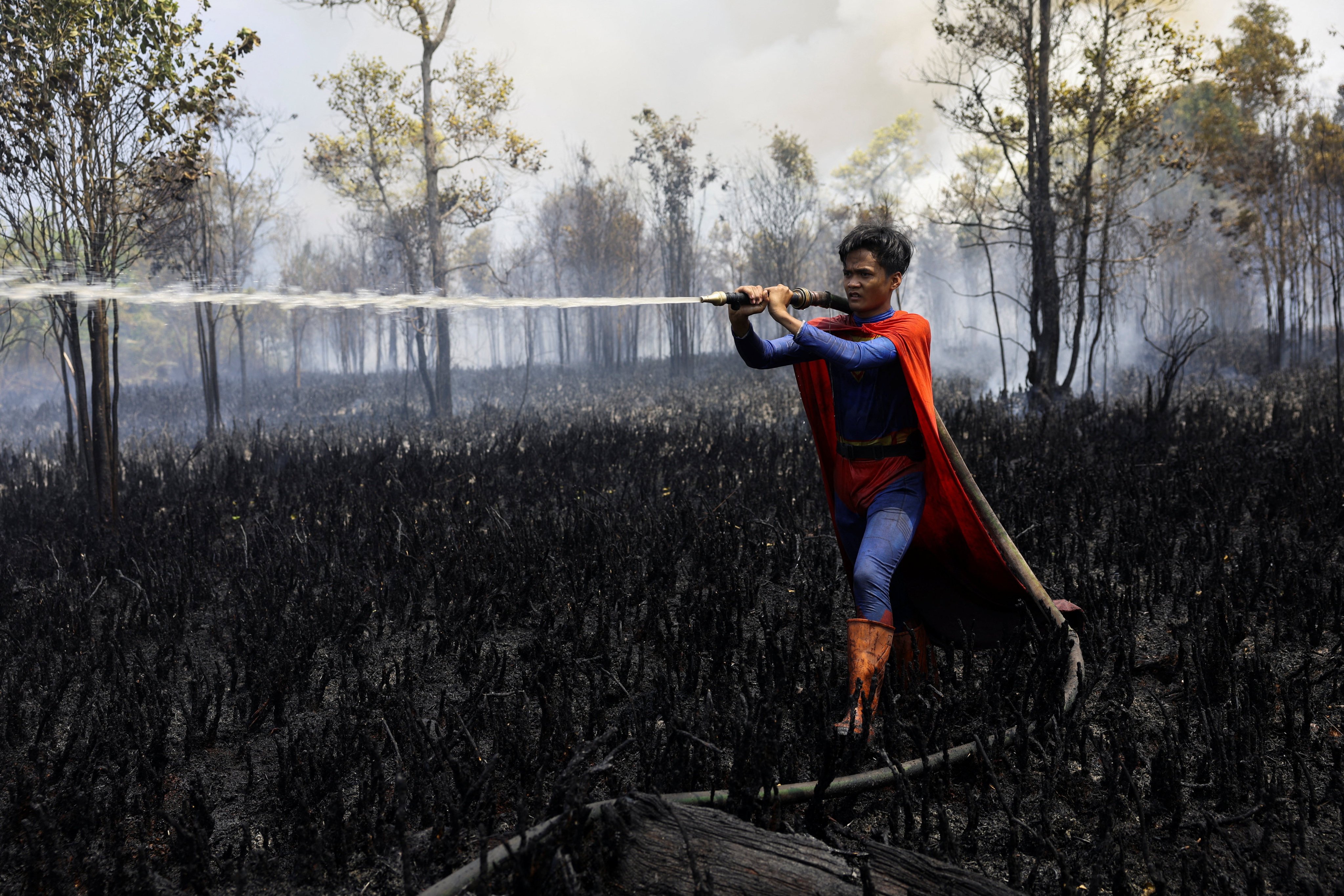 Rudiyansah, wears a Superman costume while extinguishing a fire at a wildfire-affected area in Palangka Raya, Central Kalimantan, Indonesia, on August 14. Photo: Reuters