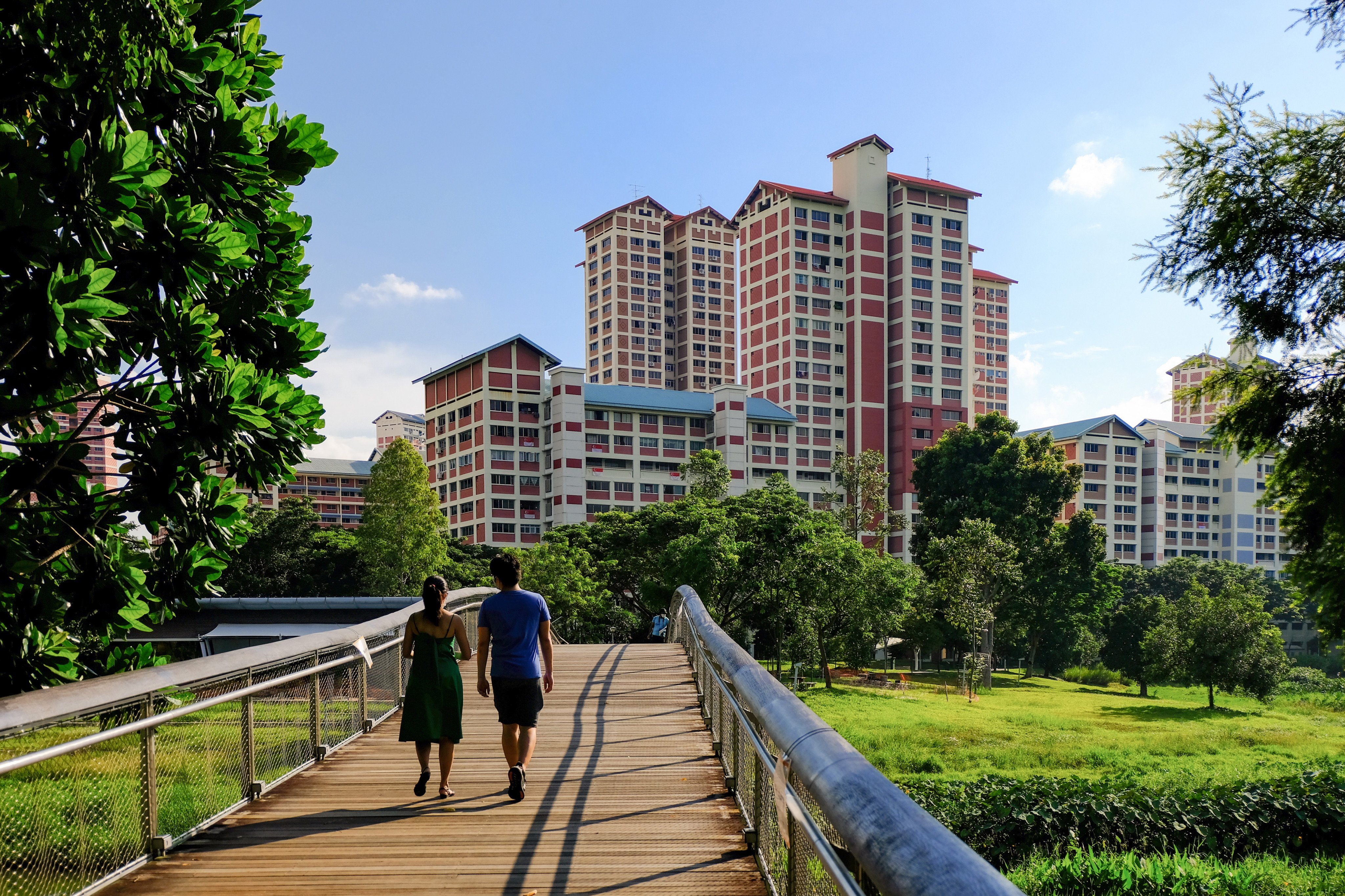 A couple walk in a  neighbourhood park towards blocks of flats in Singapore. Photo: Shutterstock