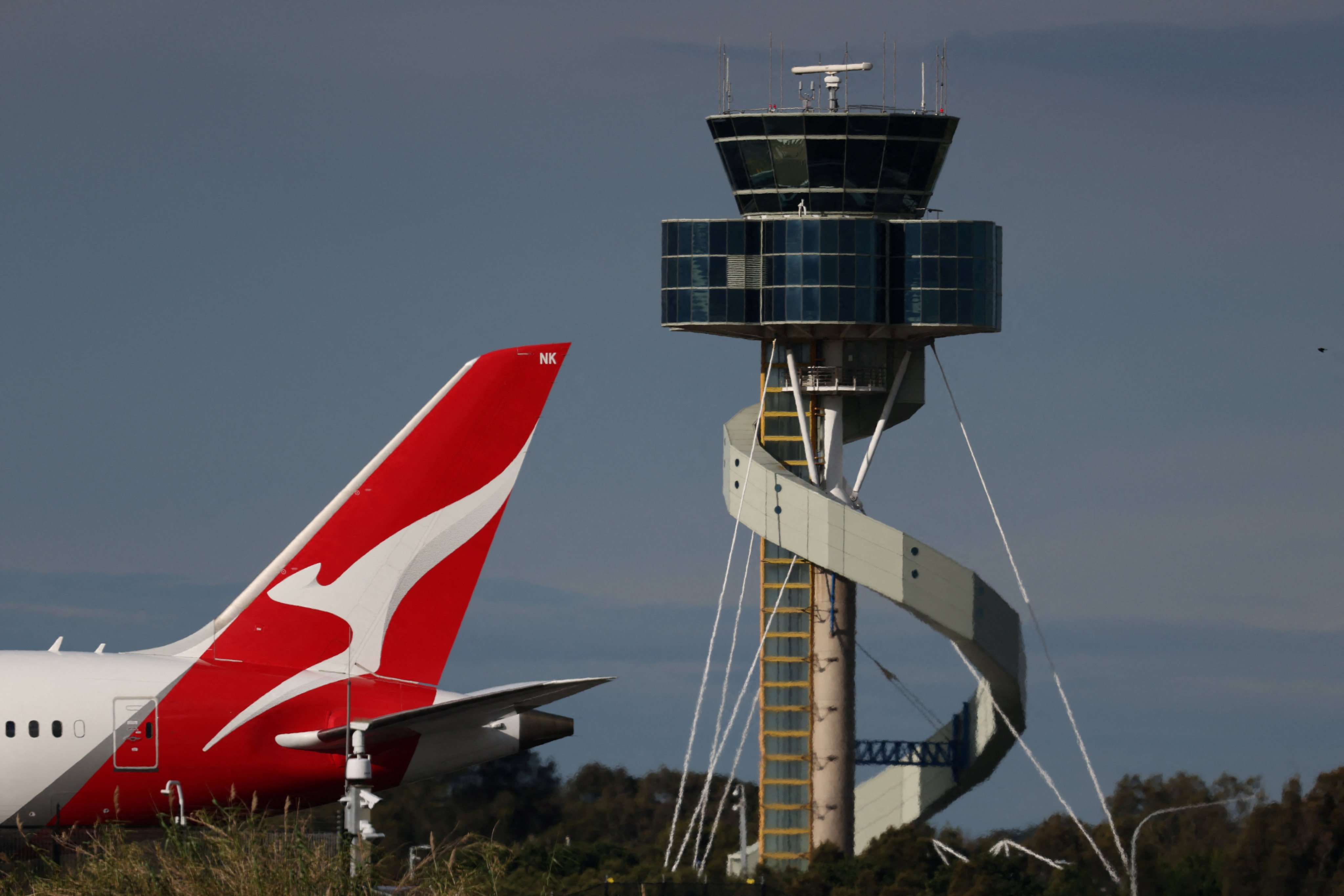 A Qantas plane passes an air traffic control tower at Sydney Airport, Australia, on Friday. There have been four near misses at the airport over the past month. Photo: Reuters