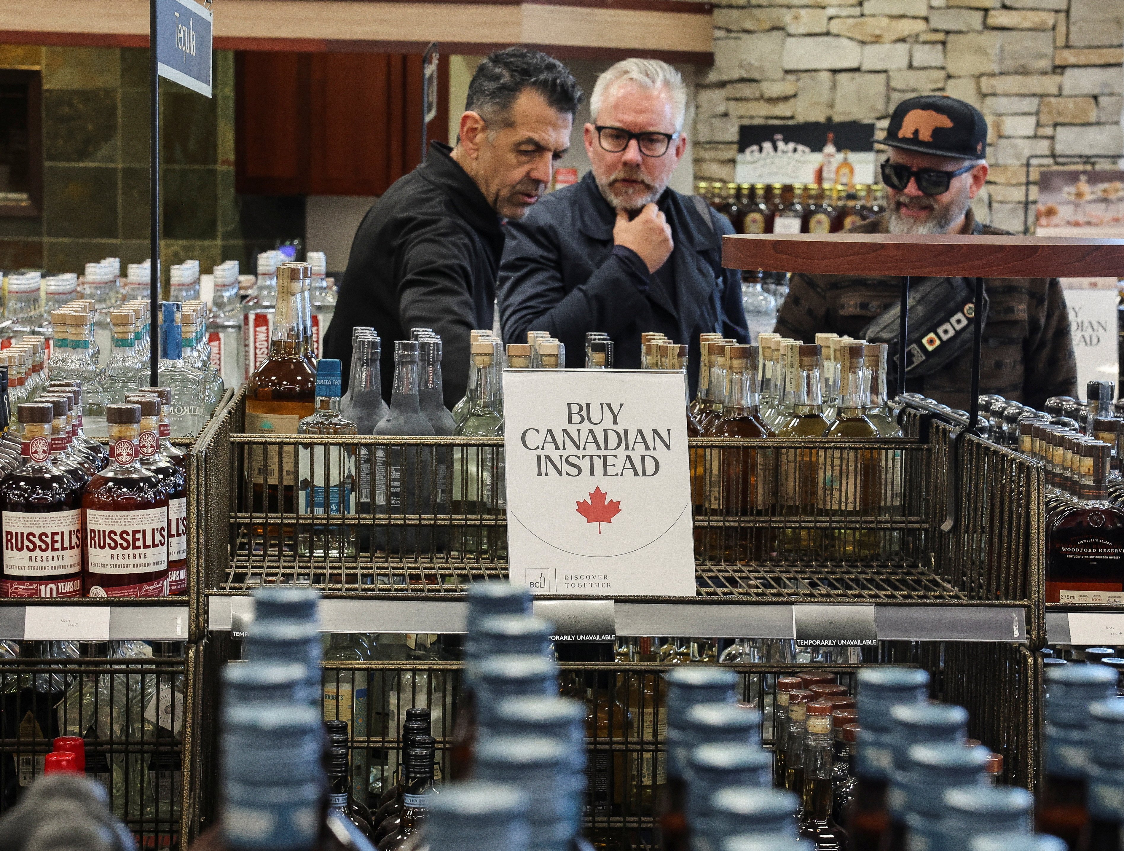 Shoppers stand by empty shelves with signs reading “Buy Canadian Instead” after the top five US liquor brands were removed from sale at a liquor store in Vancouver, Canada, as part of a response to US President Donald Trump’s tariffs on Canadian goods, on February 2, 2025. Photo: Reuters