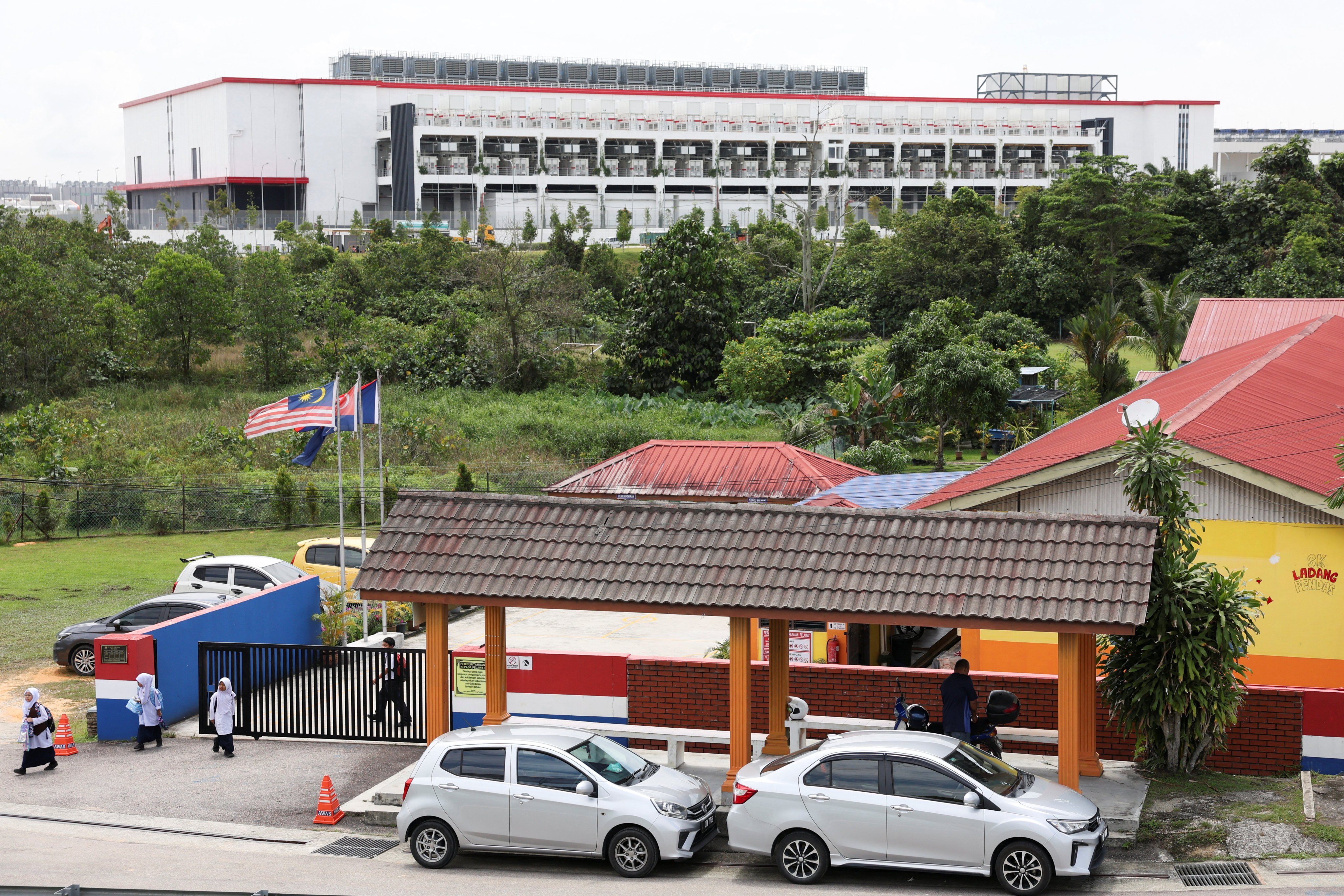 Pupils leave a school in Malaysia’s Johor state as a data centre stands in the background. Photo: Reuters