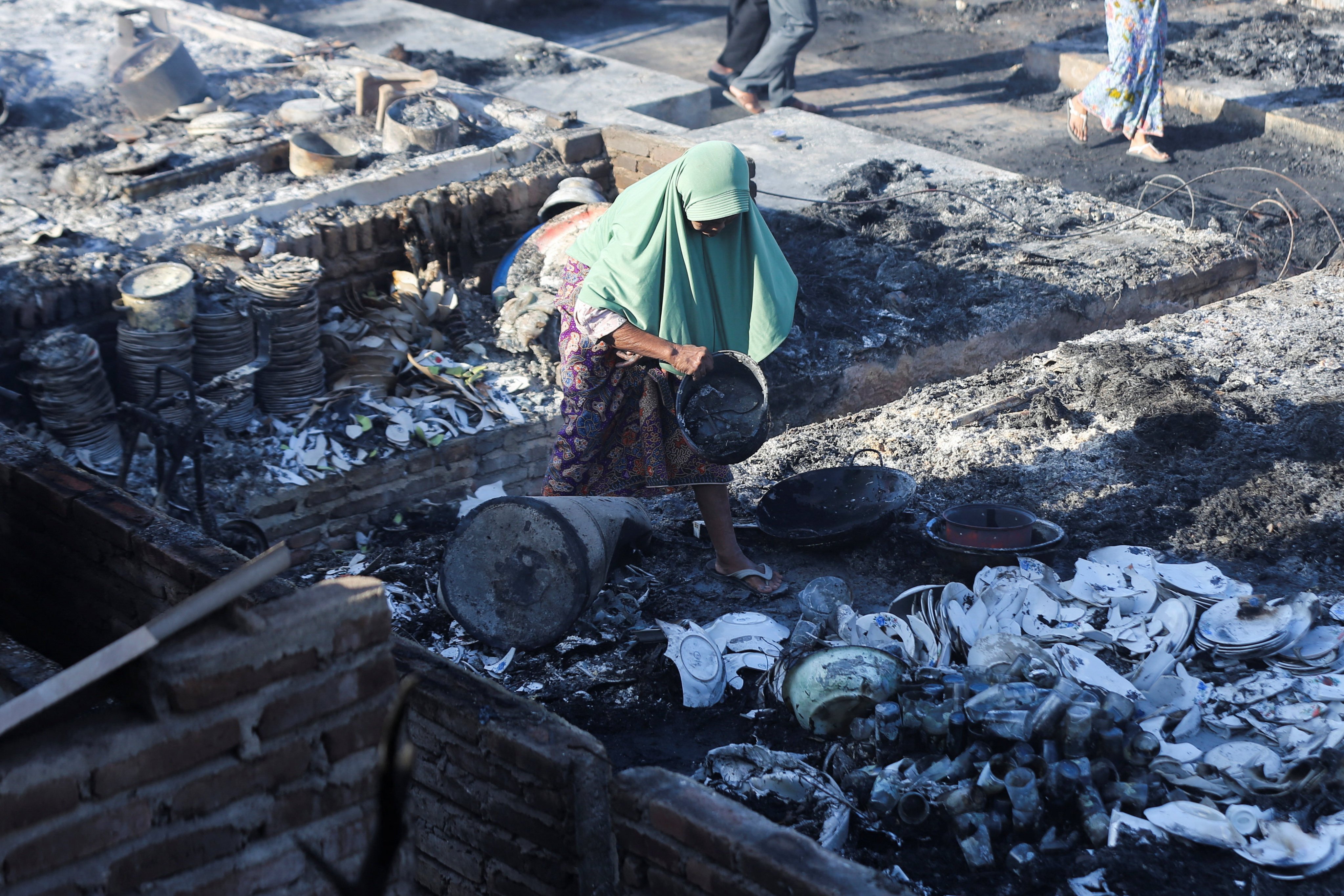 An elderly woman collects useable goods from the remains of her house at Sade, a traditional Sasak village that caught fire overnight in West Nusa Tenggara province, Indonesia, on Sunday. Photo: Reuters