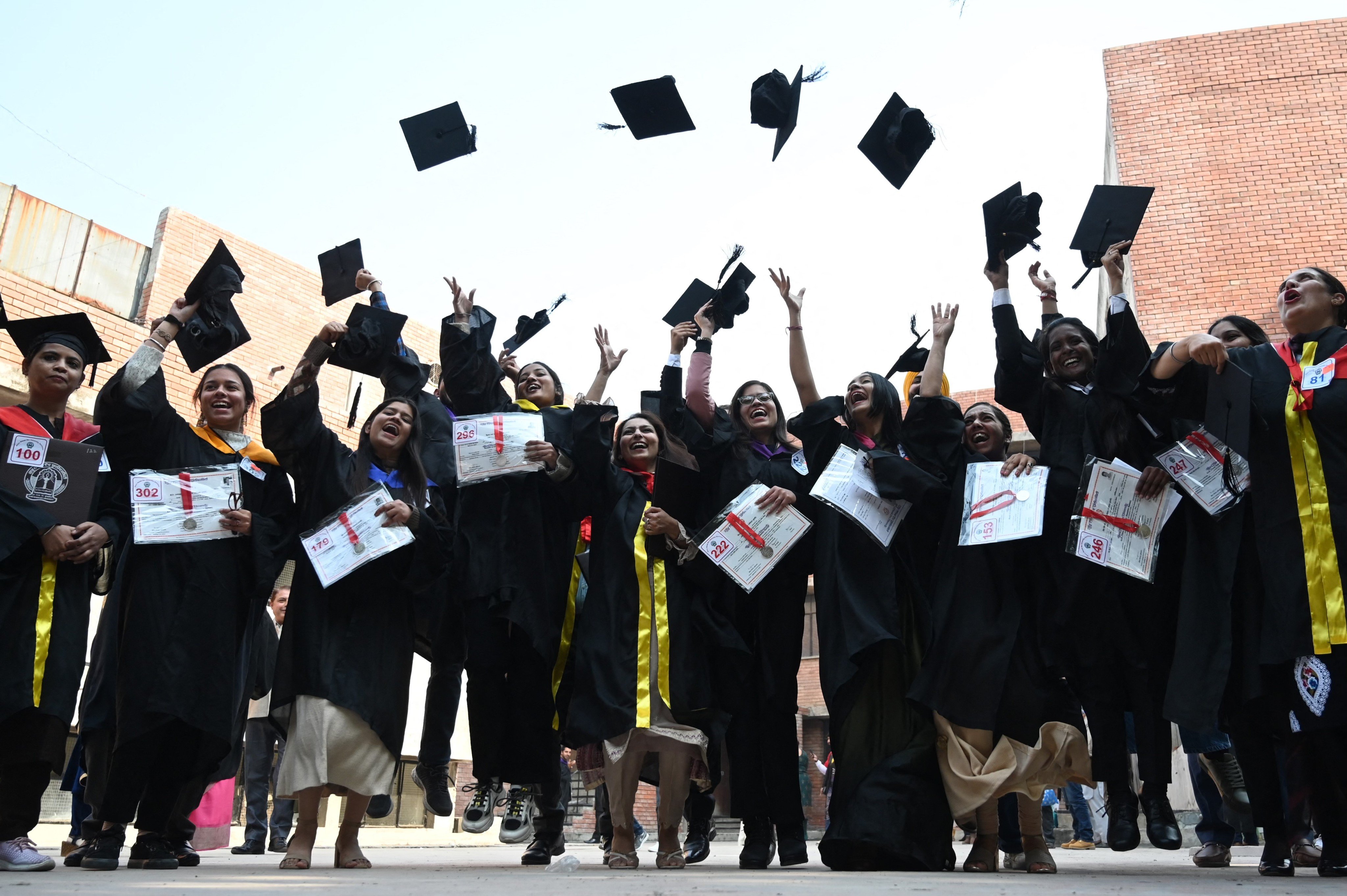 Students throw their graduation hats in the air at a university in Amritsar, India, in 2022. Photo: Nanu/AFP