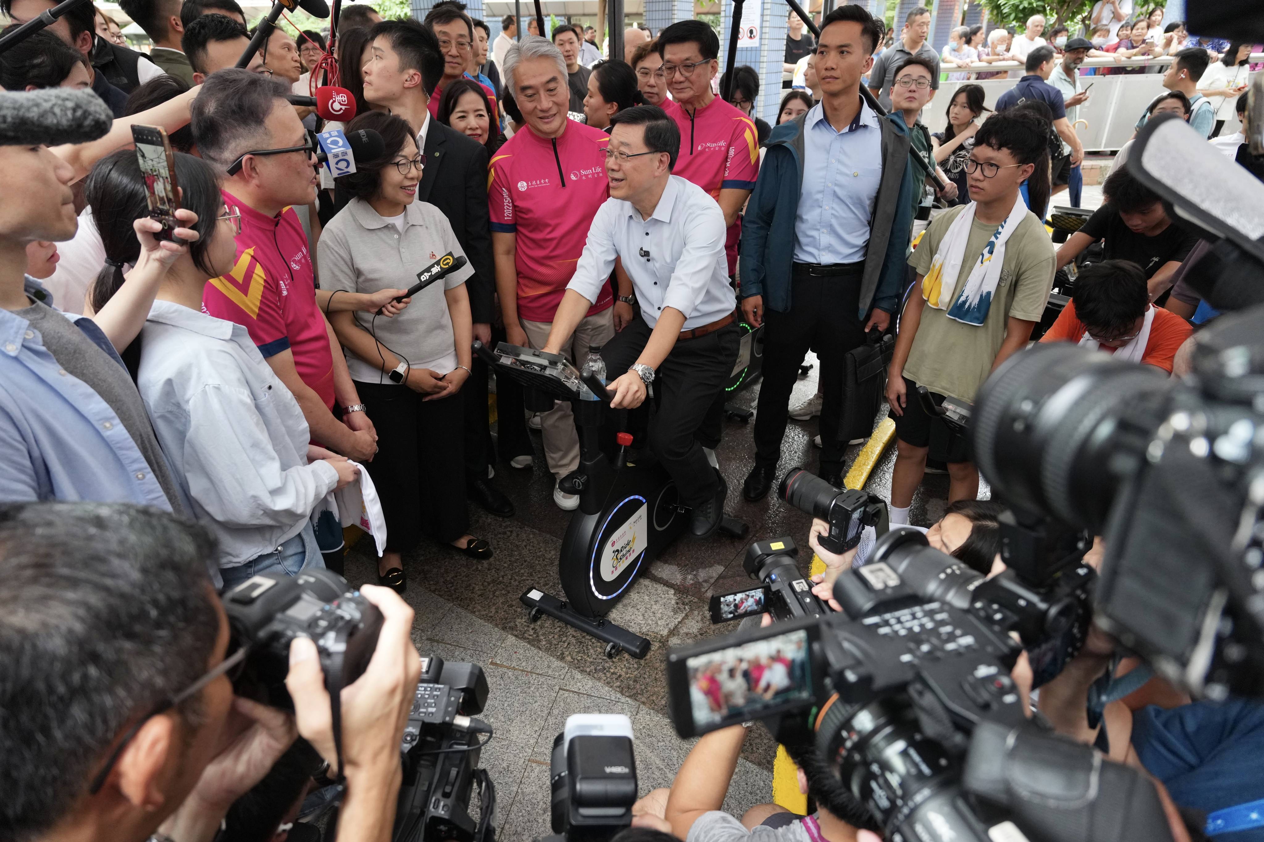 City leader John Lee tries out an exercise bike during his visit to Un Chau Estate in  Sham Shui Po. Photo: Karma Lo