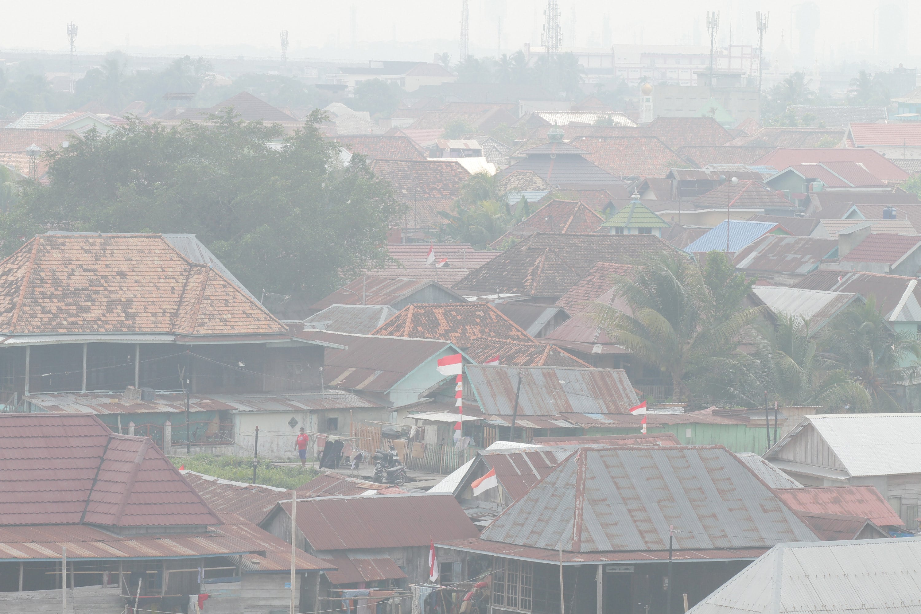 A man stands among houses as haze from wildfires blankets the city of Palembang, South Sumatra, Indonesia, on Tuesday. Photo: AP