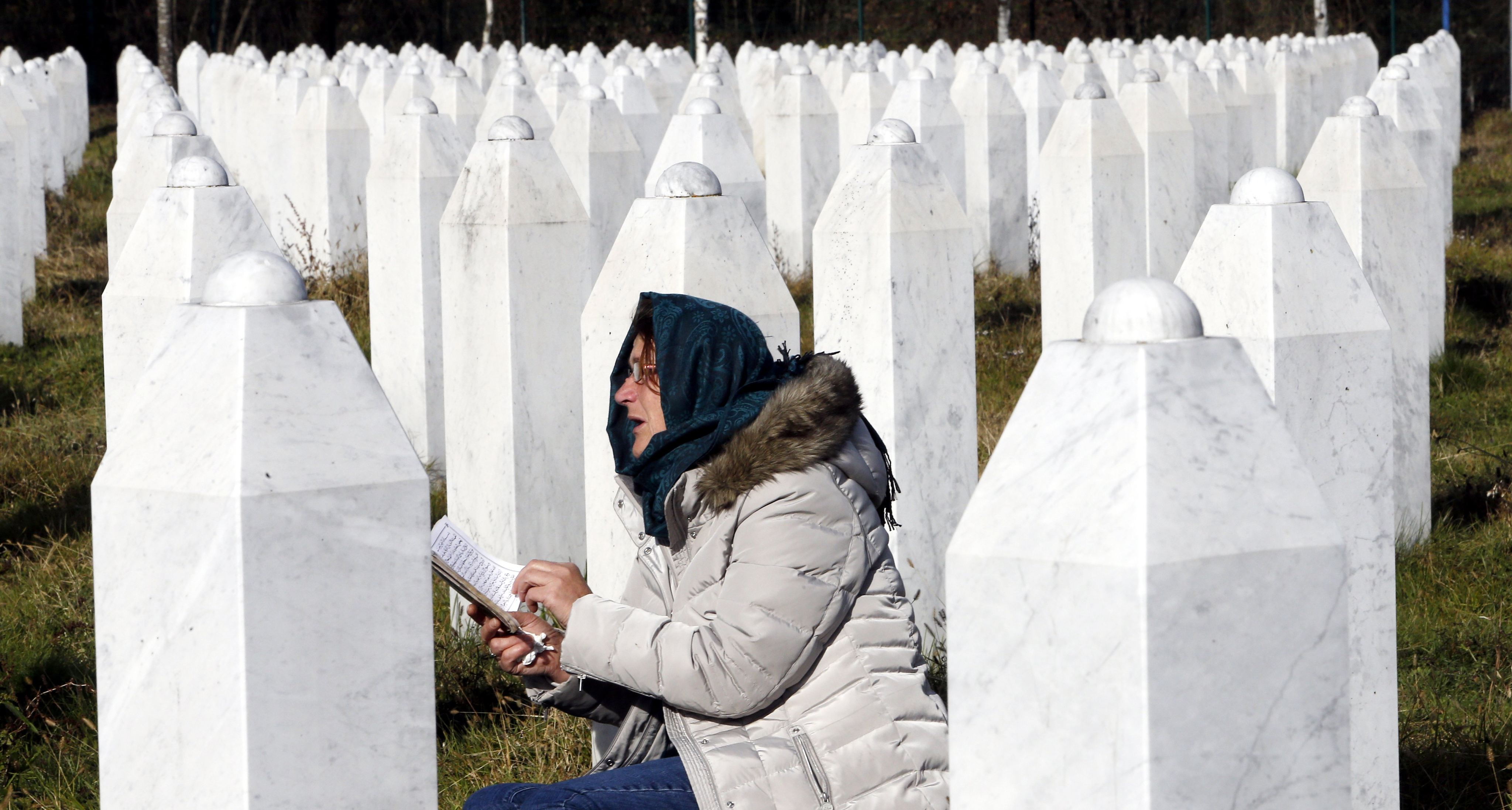 A woman reads a prayer at the grave of her relative in Potocari, Bosnia and Herzegovina, in 2017. Photo: EPA-EFE