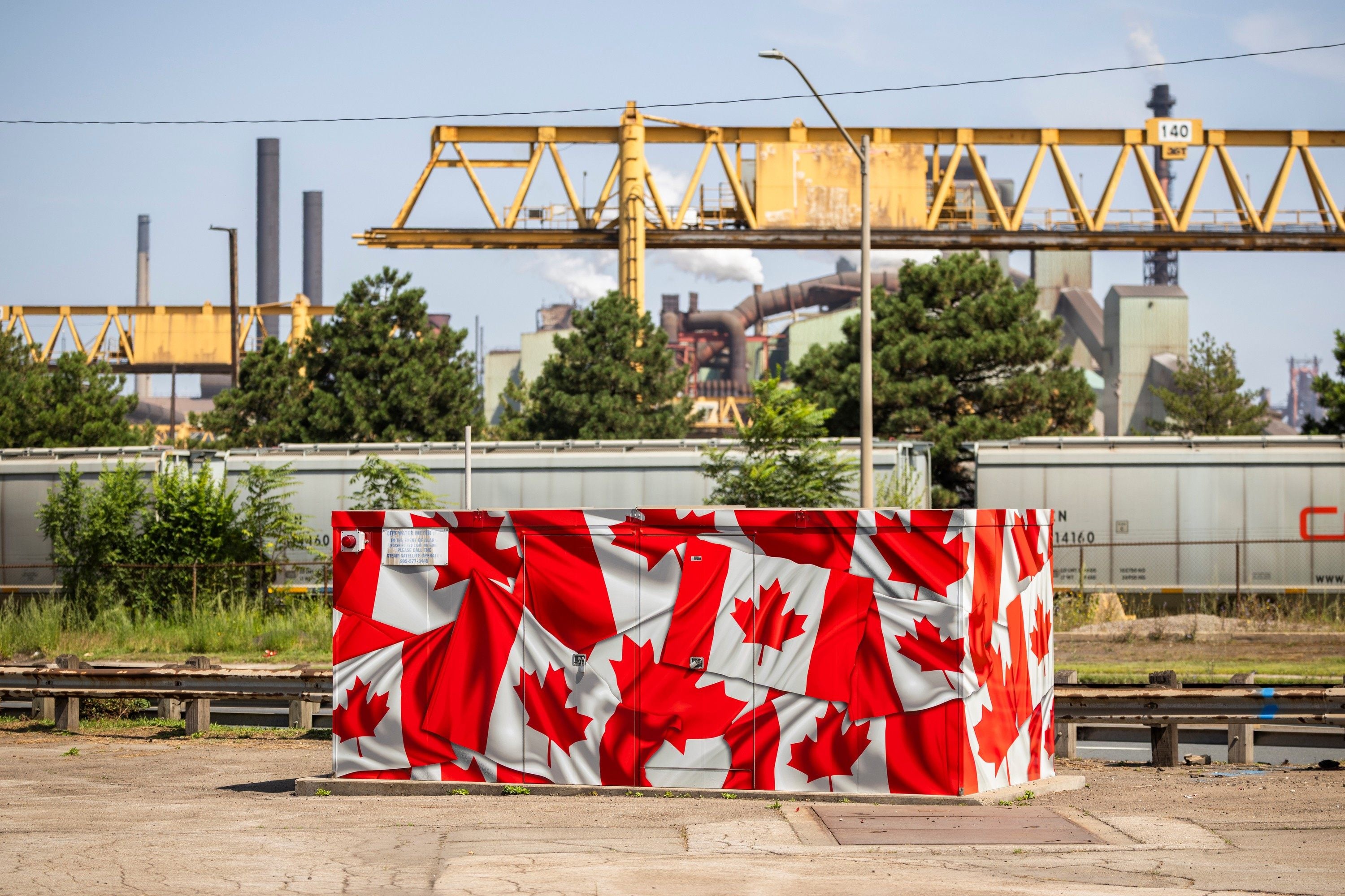 A utilities box covered in Canadian flags sits in front of a steel plant in Hamilton, Ontario, Canada, on August 20. Although Canada’s economy will bear the brunt of a full-blown trade war, the US will suffer, too. Photo: The Canadian Press via AP