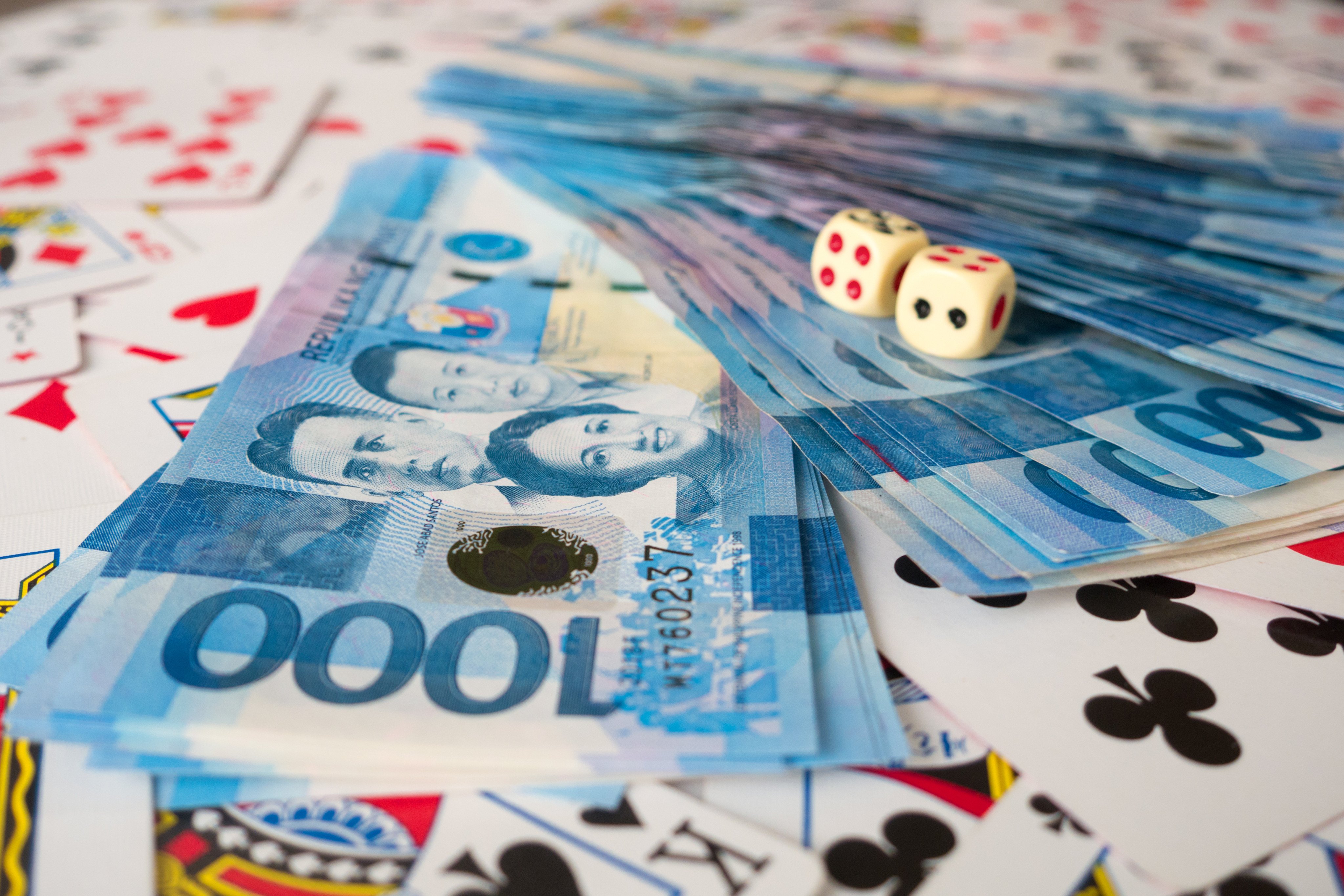 Philippine peso banknotes on a pile of playing cards. Korean-linked illicit gambling operations in the Philippines predate Chinese-run Pogos, observers say. Photo: Shutterstock