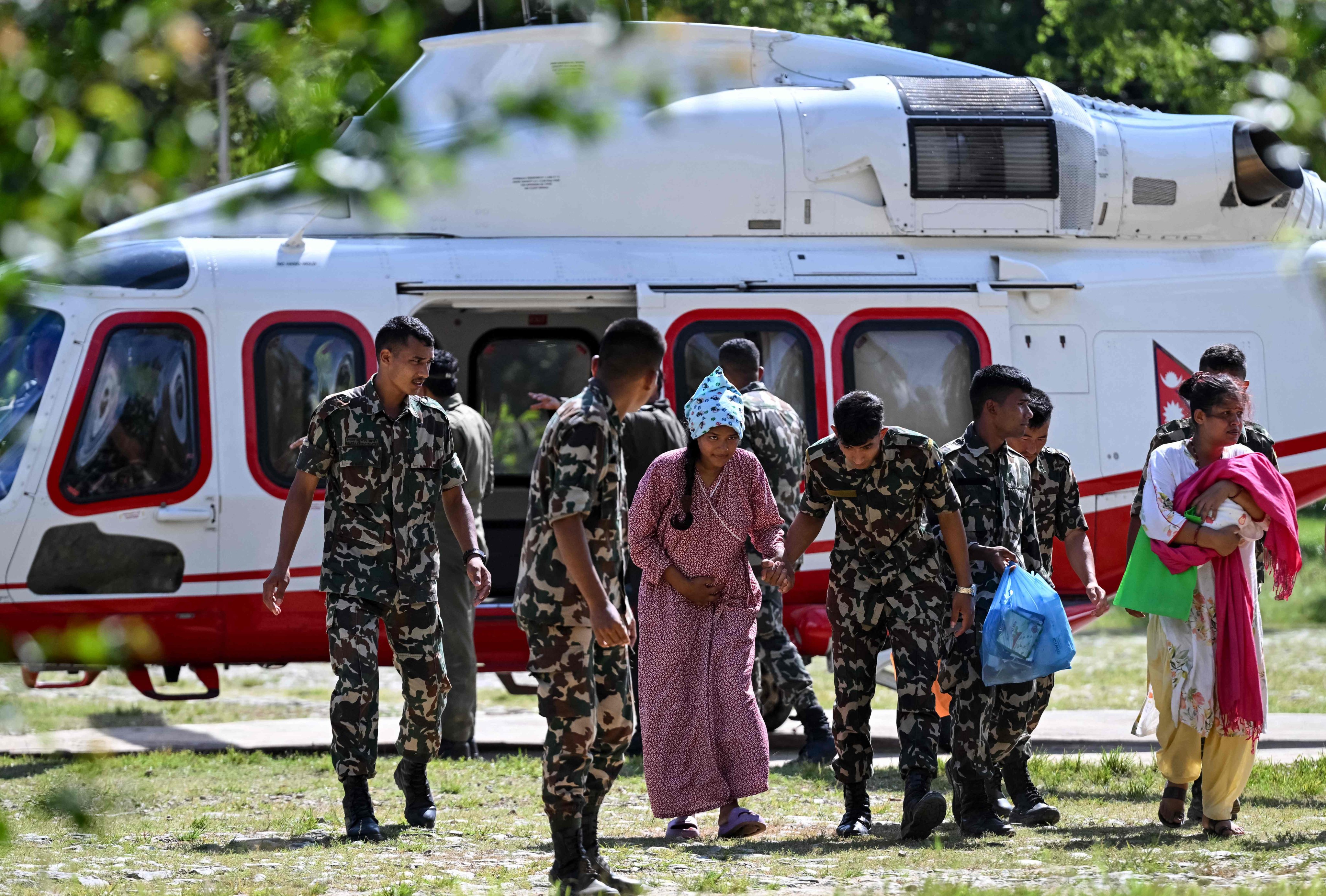 Army personnel escort a woman after her rescue from a flash flood site in Nepal’s Nuwakot district on Friday. Photo: AFP