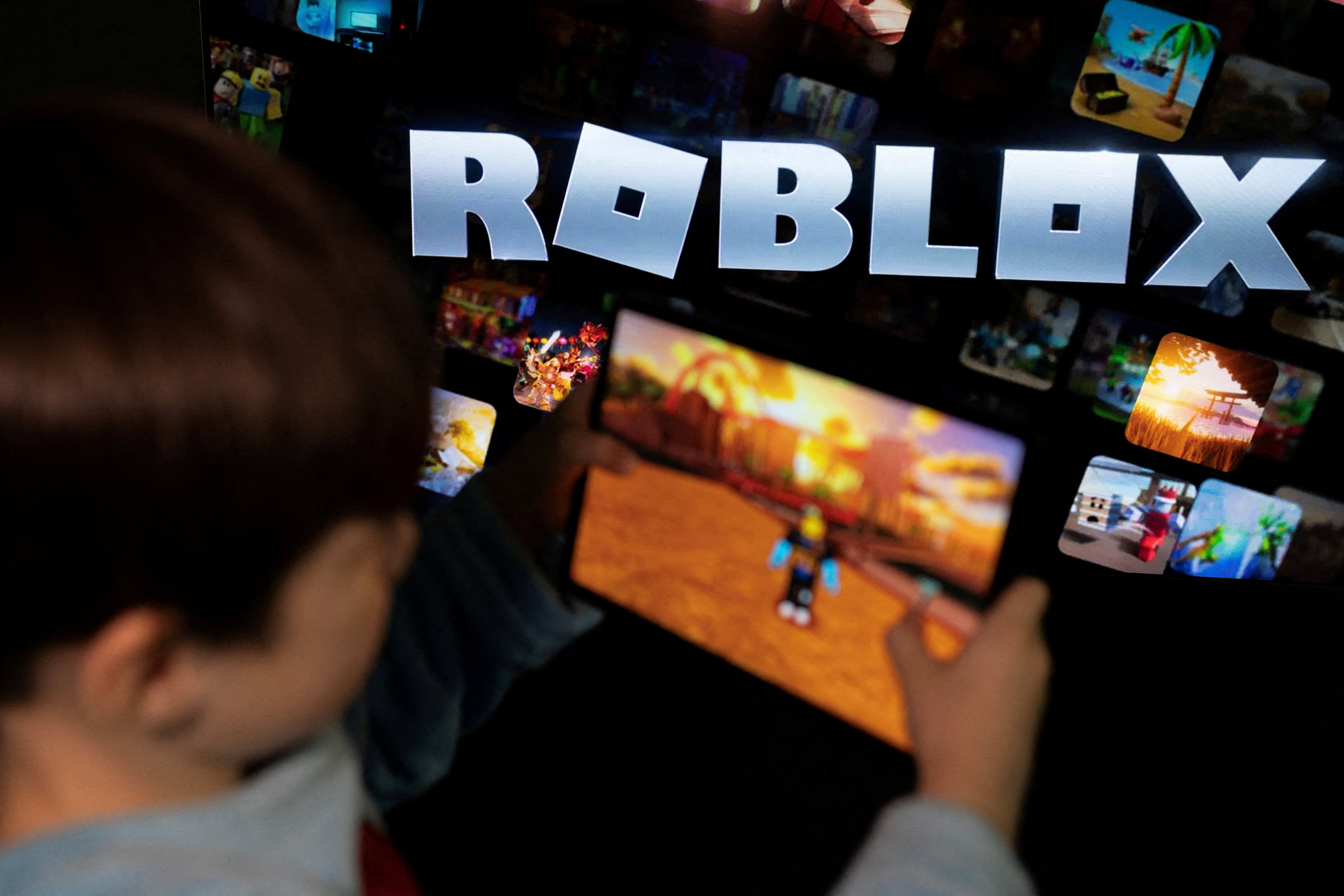 A boy plays Roblox in front of a screen displaying the platform’s logo on December 8, 2025. Photo: Reuters