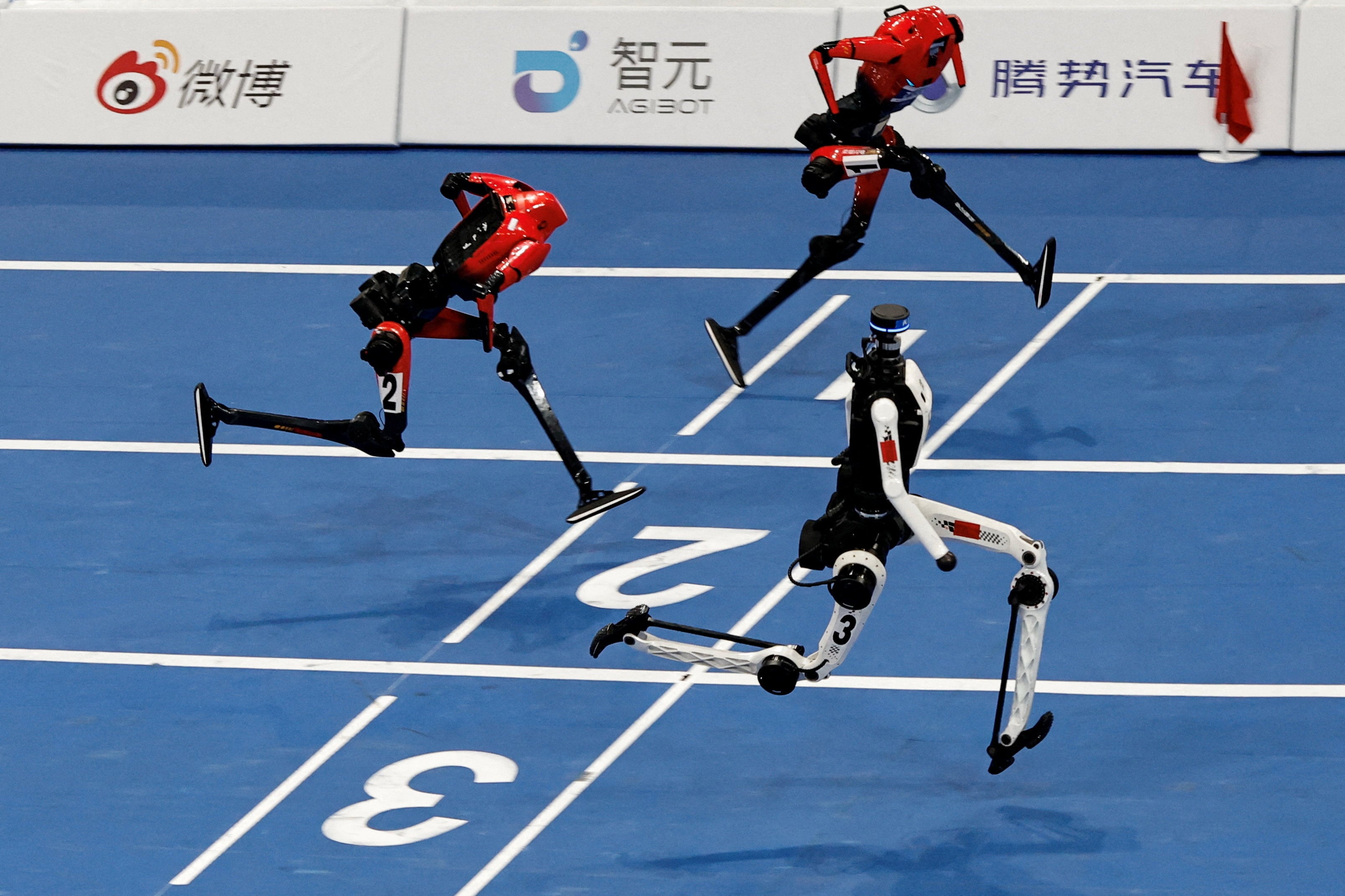 A Tiangong Ultra humanoid robot crosses the finish line in 8.86 seconds, next to Honor humanoid robots, during a 100-metre large-size group semifinal race at the 2026 World Humanoid Robot Games. Photo: Reuters