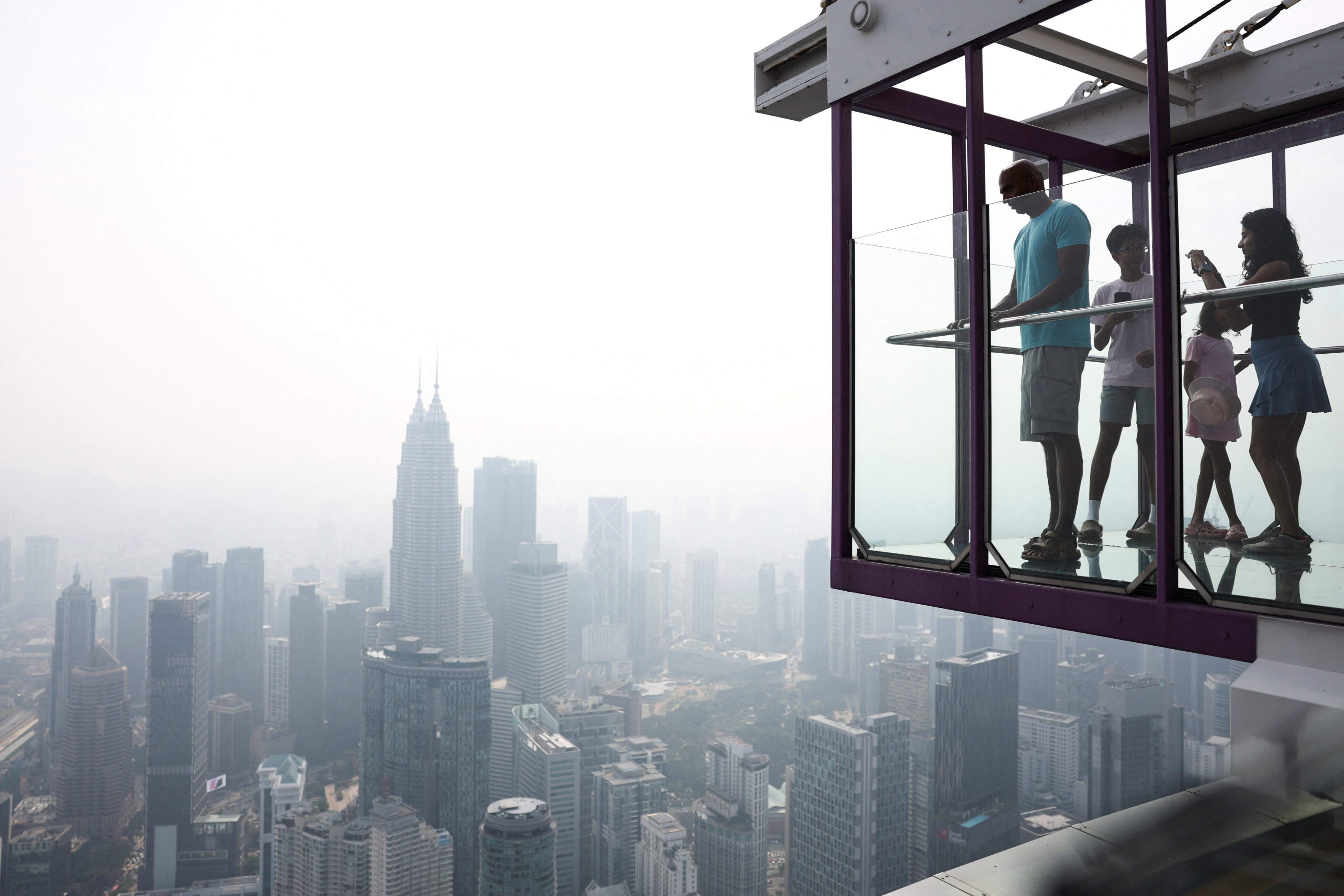 Tourists look at the city-centre skyline, shrouded in haze from wildfires in Indonesia, in Kuala Lumpur, Malaysia, in August. Photo: Reuters