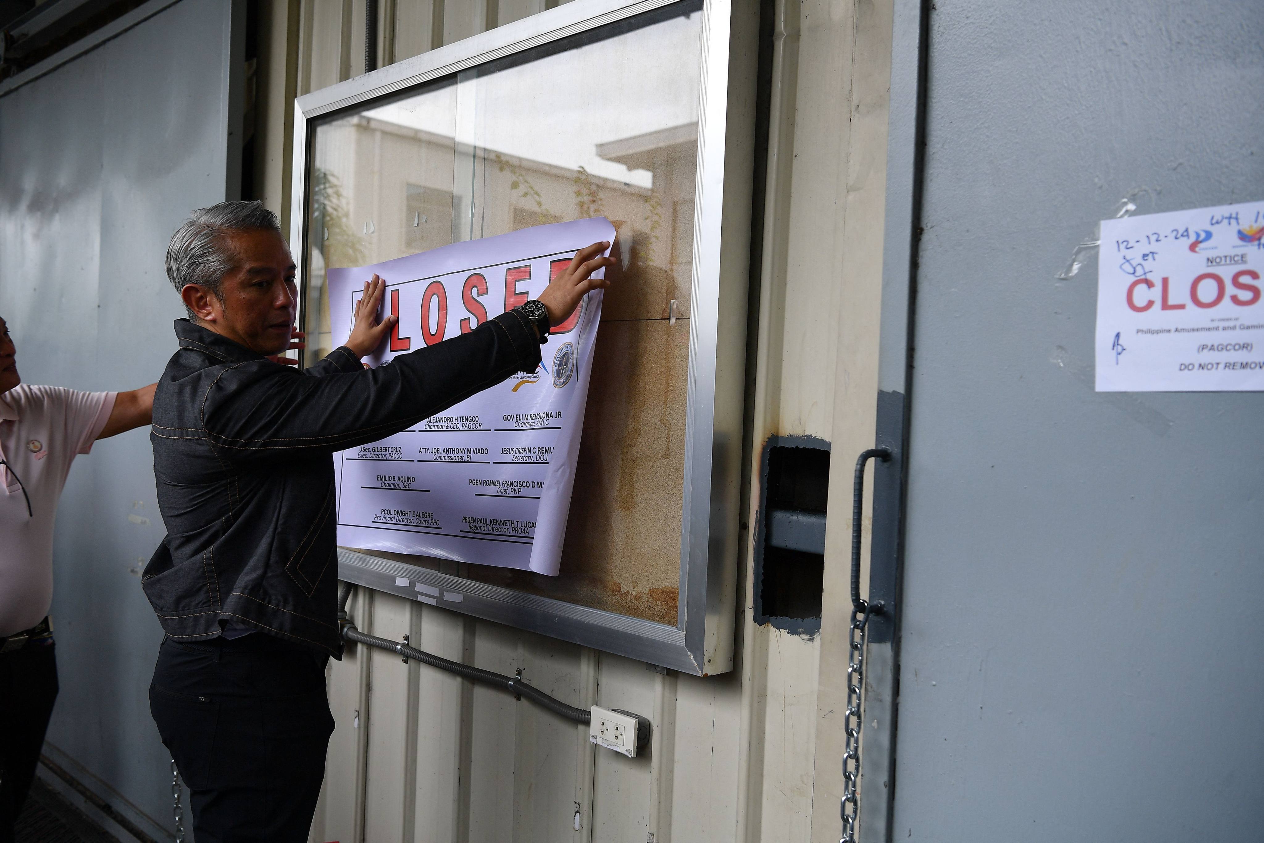 Philippine Interior Secretary Juanito Remulla places a closure sign on a former Pogo hub in Cavite province in 2024. Photo: AFP