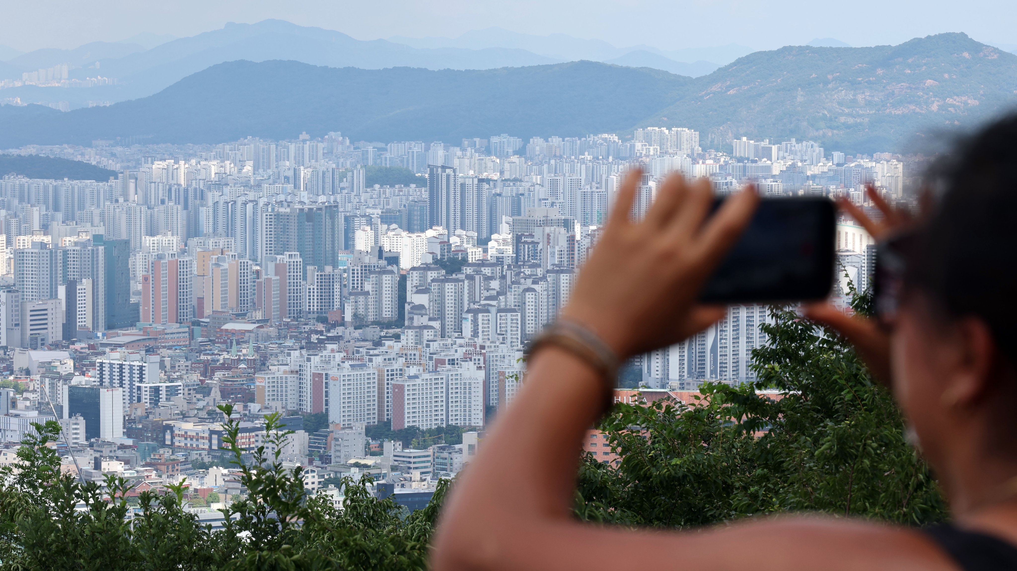 A woman takes a photo of residential complexes in Seoul on August 23. Photo: Yonhap/EPA