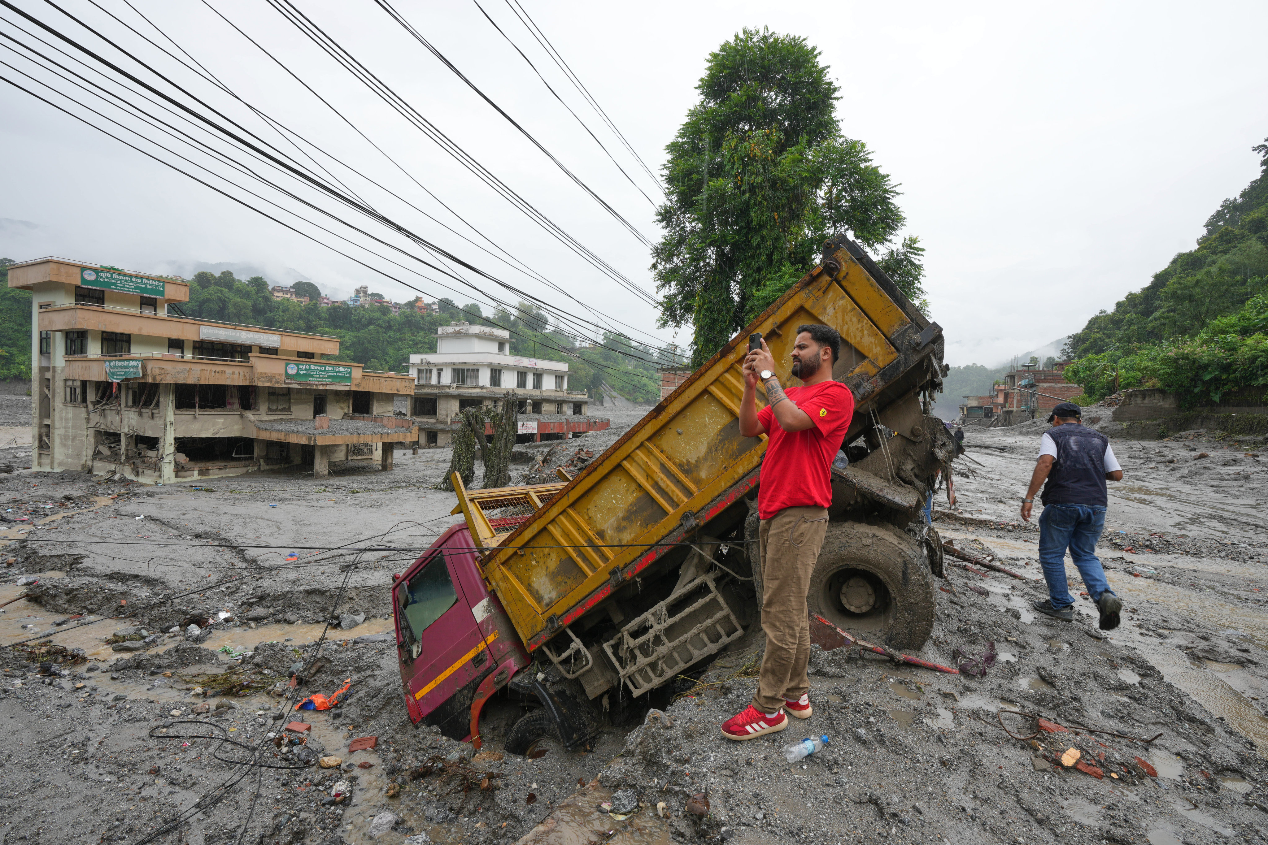 A visitor from Kathmandu records a video of the destruction caused by flash flooding in Nepal’s Nuwakot district on Saturday. Photo: AP