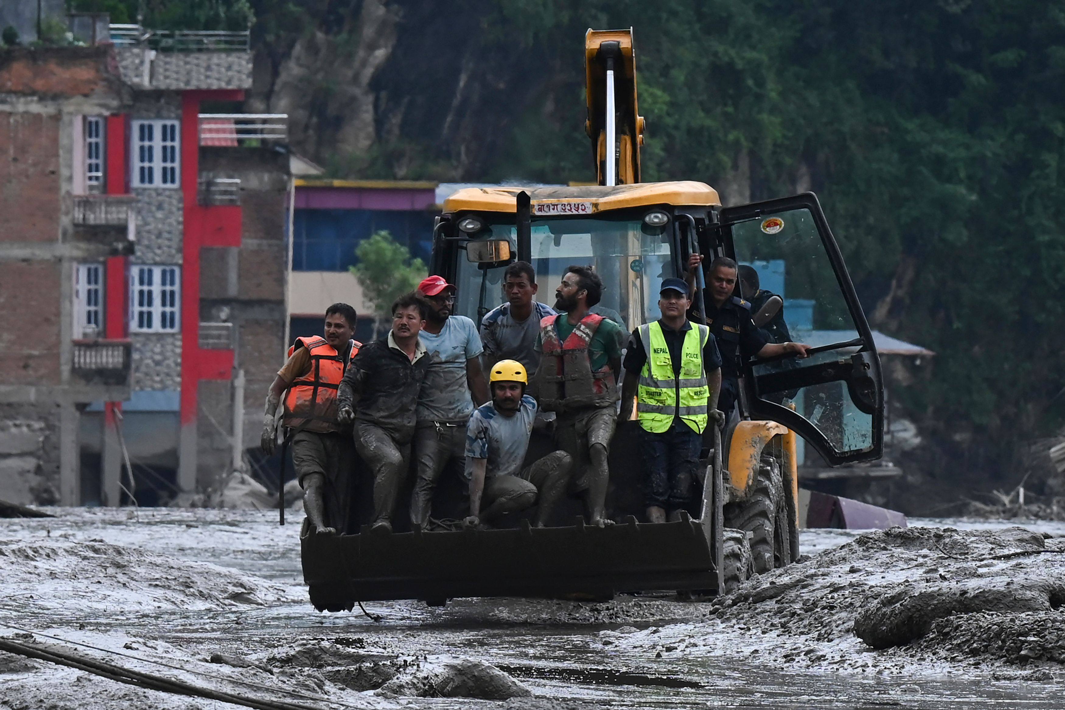 Rescuers use an excavator to transport victims and survivors along the streets submerged by mud in Devghat in Nepal’s Nuwakot district. Photo: AFP