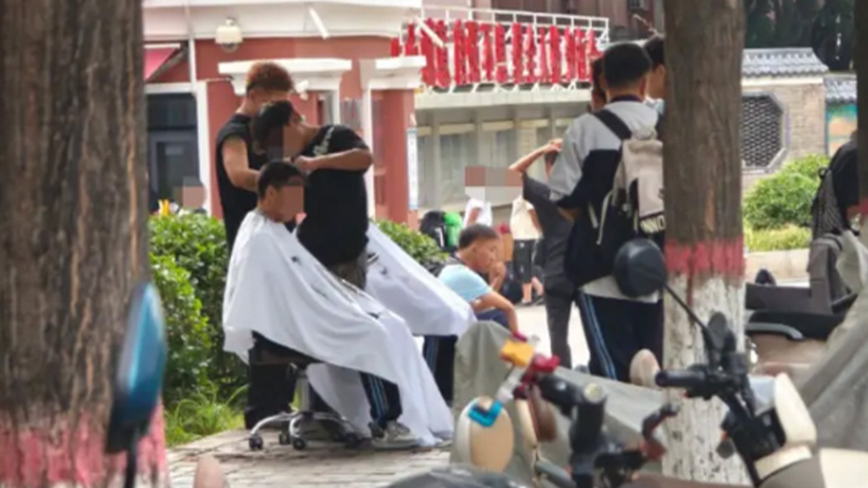 Students turn to roadside barbers after being denied entry to their schools for failing to comply with strict hair grooming requirements. Photo: Sohu