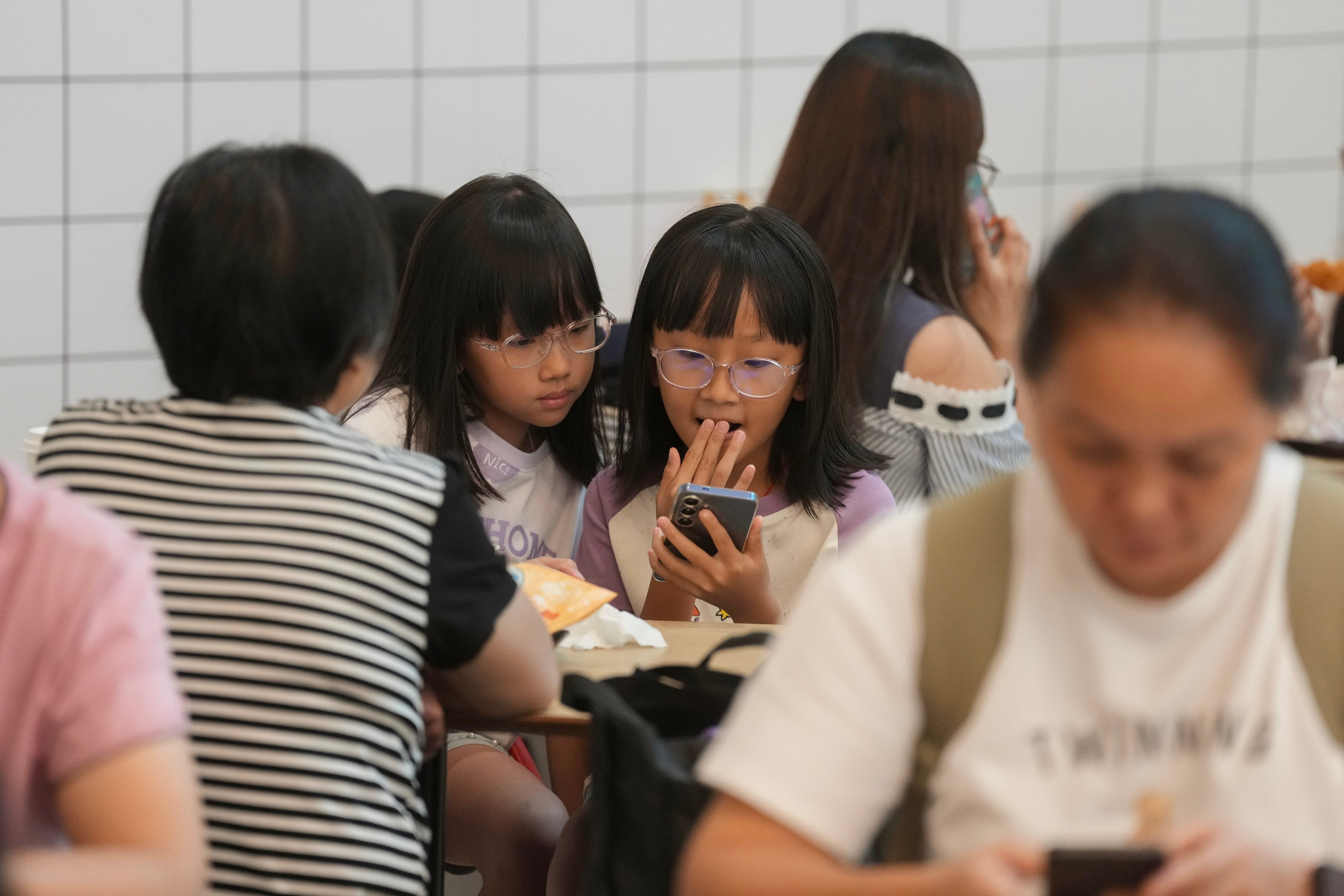 Girls focus on a smartphone inside a fast-food outlet in Kennedy Town on August 7. Photo: Karma Lo
