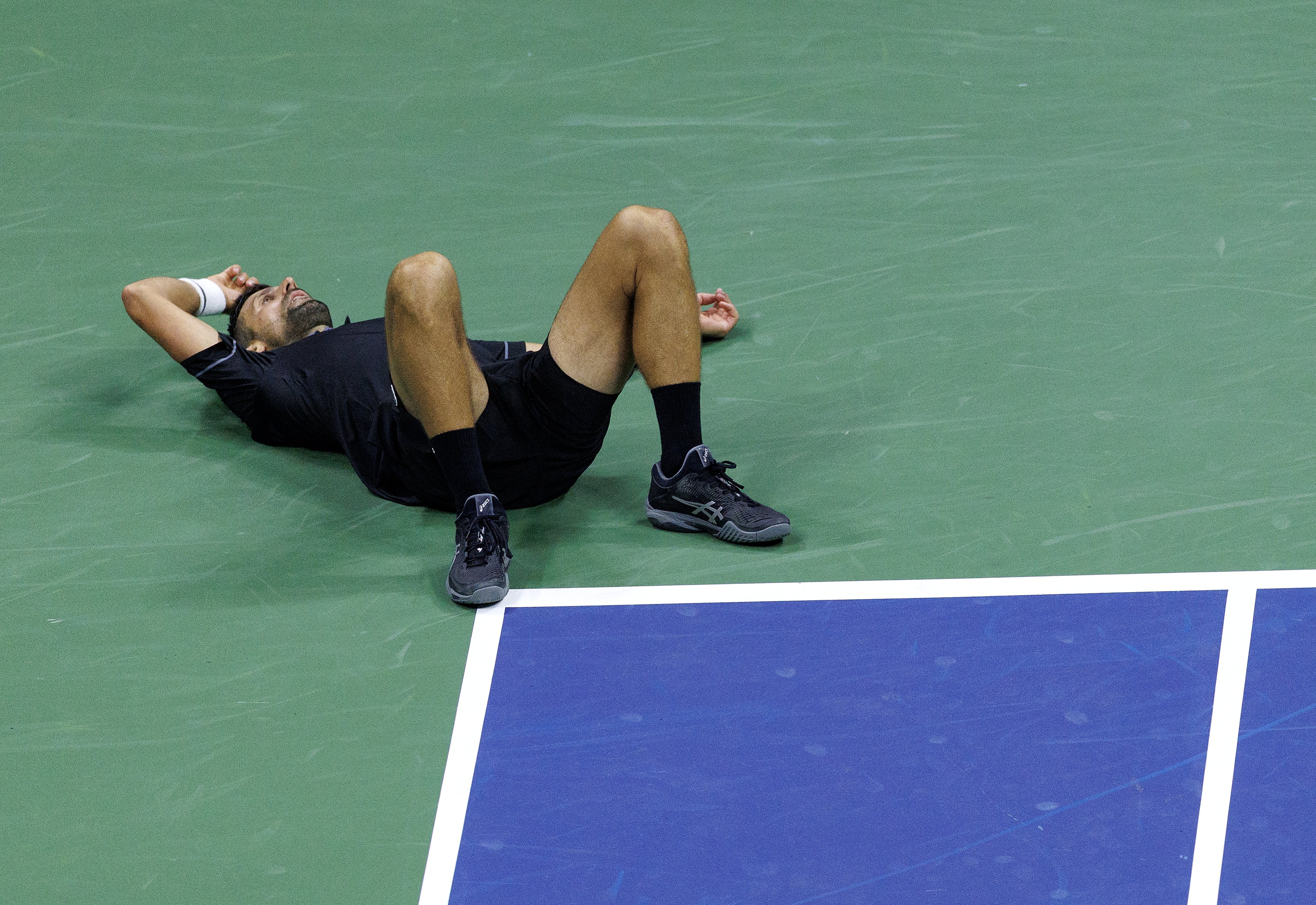 Novak Djokovic slumps to the floor during his US Open first round clash with Mariano Navone. Photo: EPA