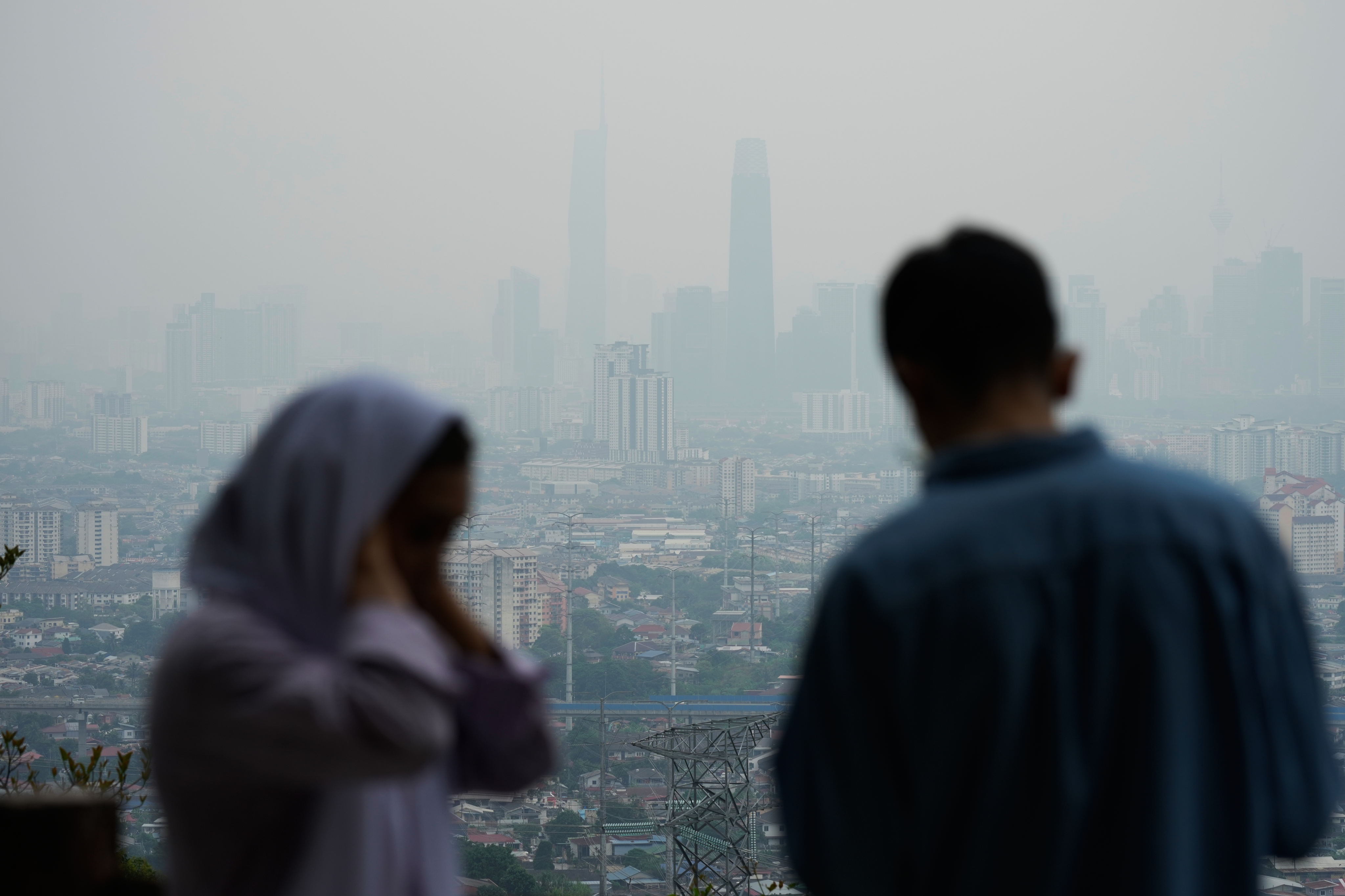 Visitors take photographs from a lookout point overlooking a hazy Kuala Lumpur skyline on August 14. Photo: AP